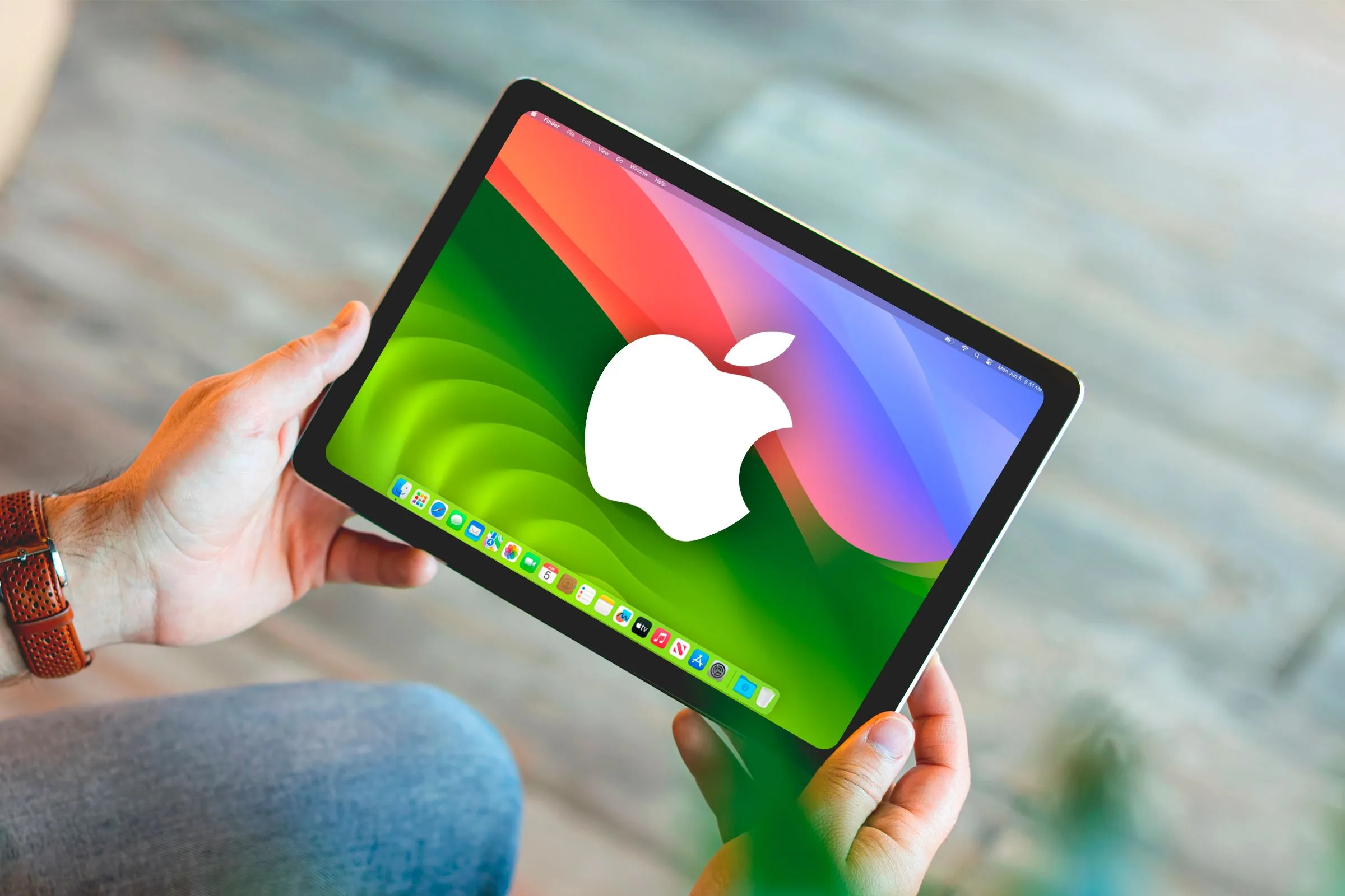 Một bàn tay cầm iPad hiển thị giao diện giống macOS với logo Apple trên màn hình.