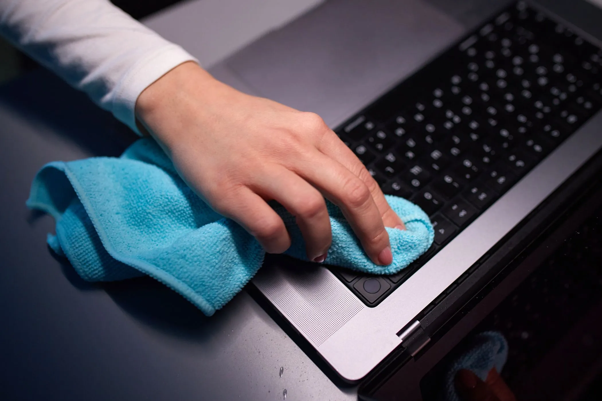 Một người đang sử dụng khăn vải sợi nhỏ để vệ sinh màn hình máy MacBook Pro, bước chuẩn bị quan trọng trước khi bán Mac cũ.