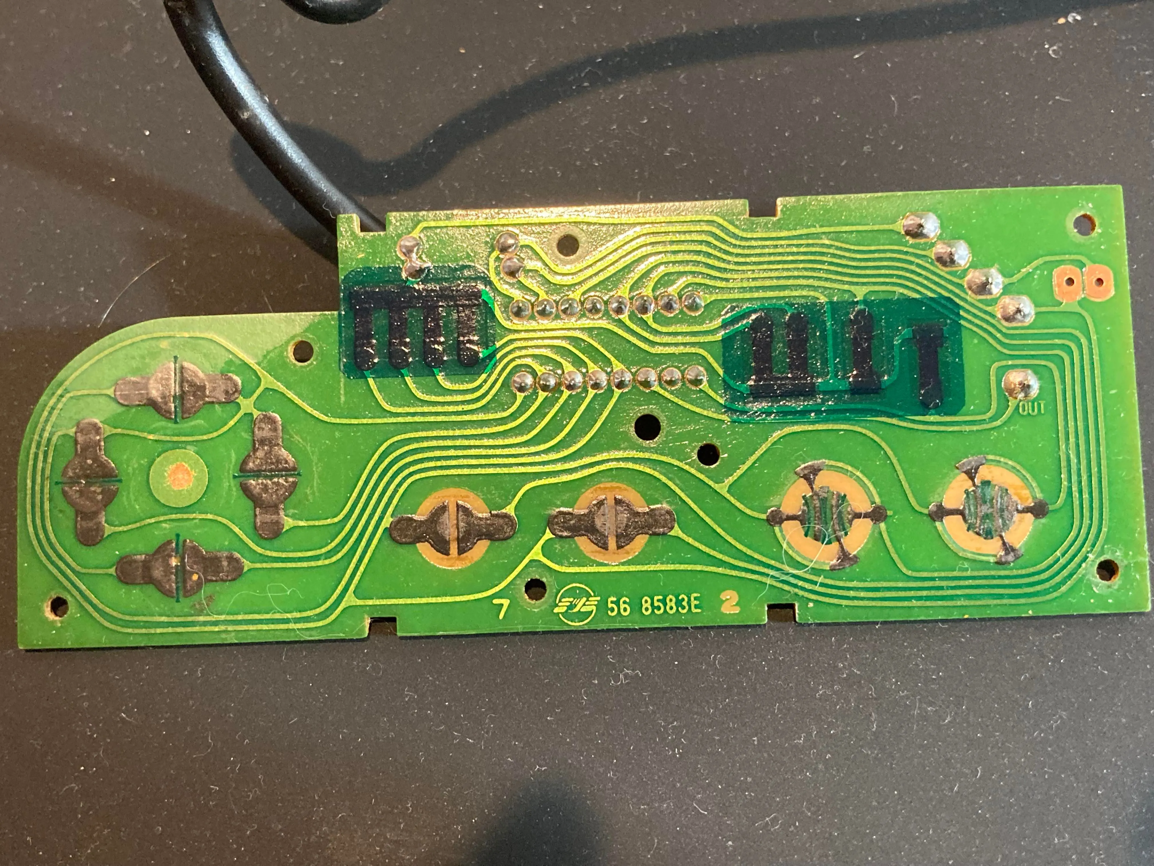 Bảng mạch in (PCB) bên trong tay cầm NES nhìn từ mặt trước, cho thấy chip và các điểm tiếp xúc