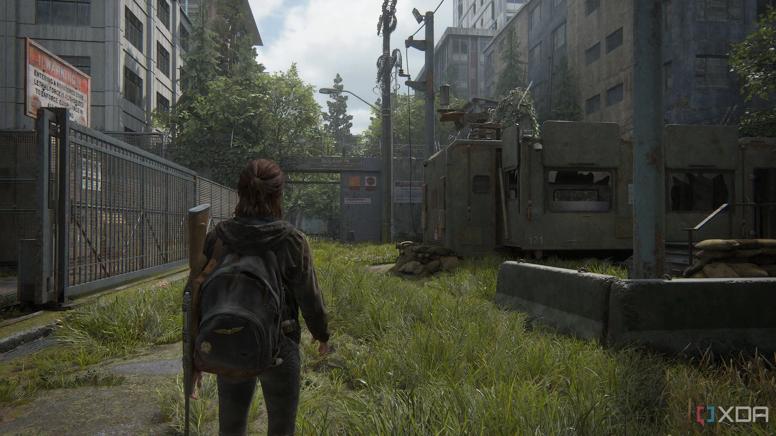 A screenshot from the game The Last of Us Part II Remastered on PC, showing Ellie walking through a military compound.