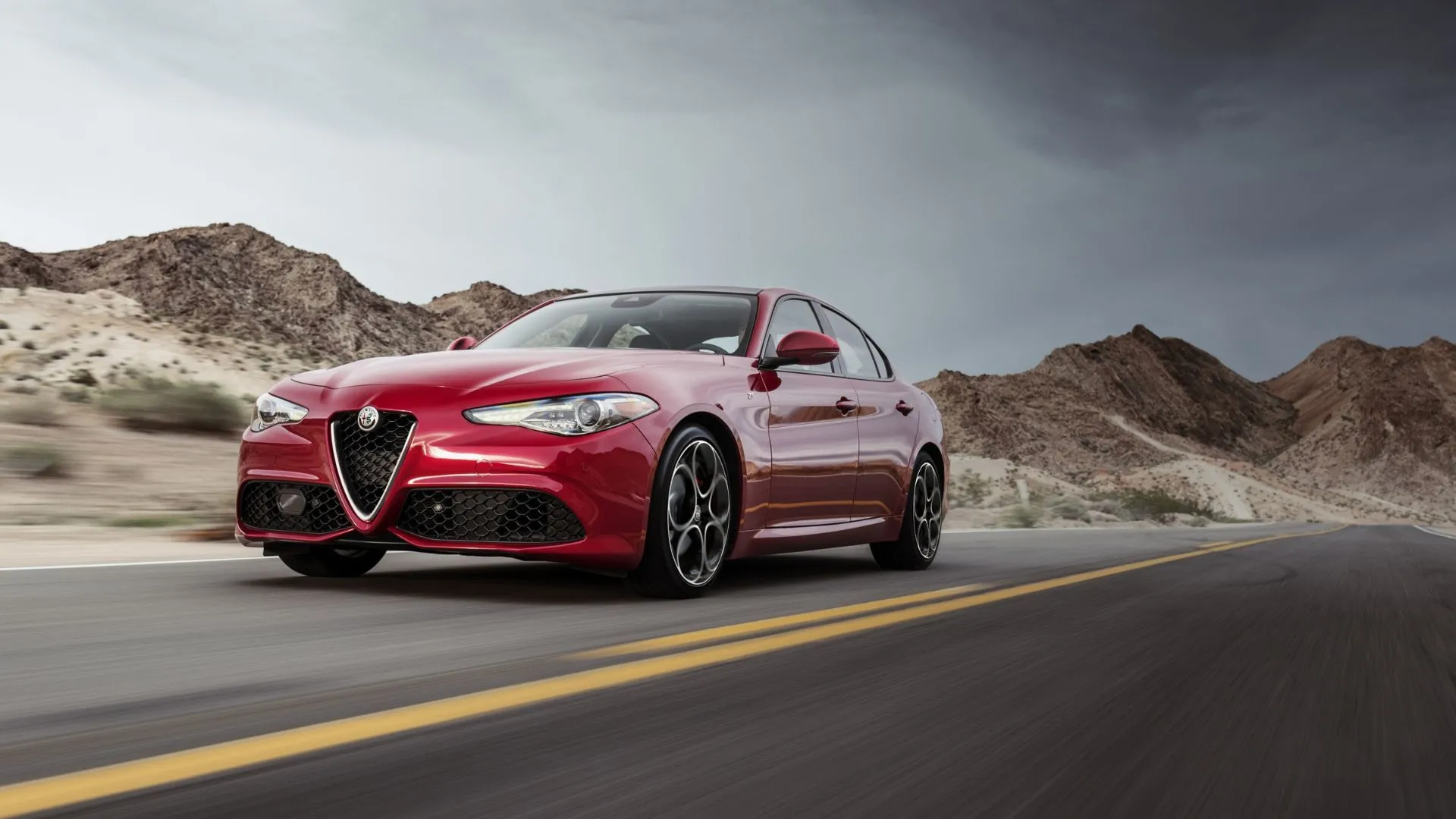 Alfa Romeo Giulia màu đỏ nổi bật trên con đường nông thôn, phản ánh phong cách thể thao và hiệu suất mạnh mẽ của xe