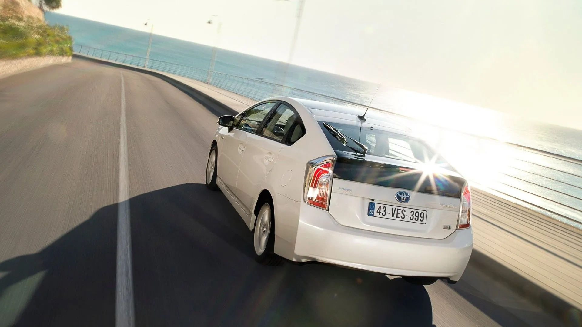 Ảnh góc 3/4 phía sau của Toyota Prius 2012 đang di chuyển, minh họa khả năng tiết kiệm nhiên liệu vượt trội của dòng xe hybrid này.