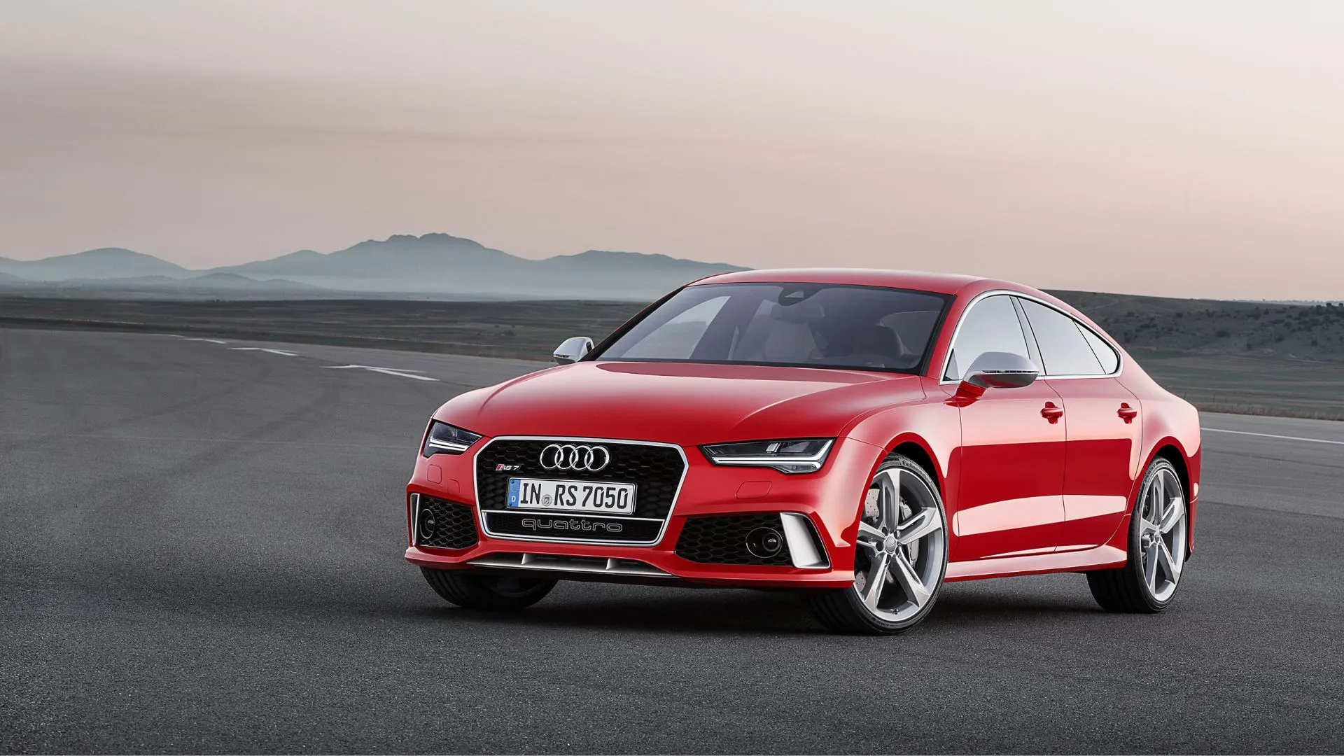 Audi RS7 2015 màu đỏ đỗ trên đường với núi non phía sau