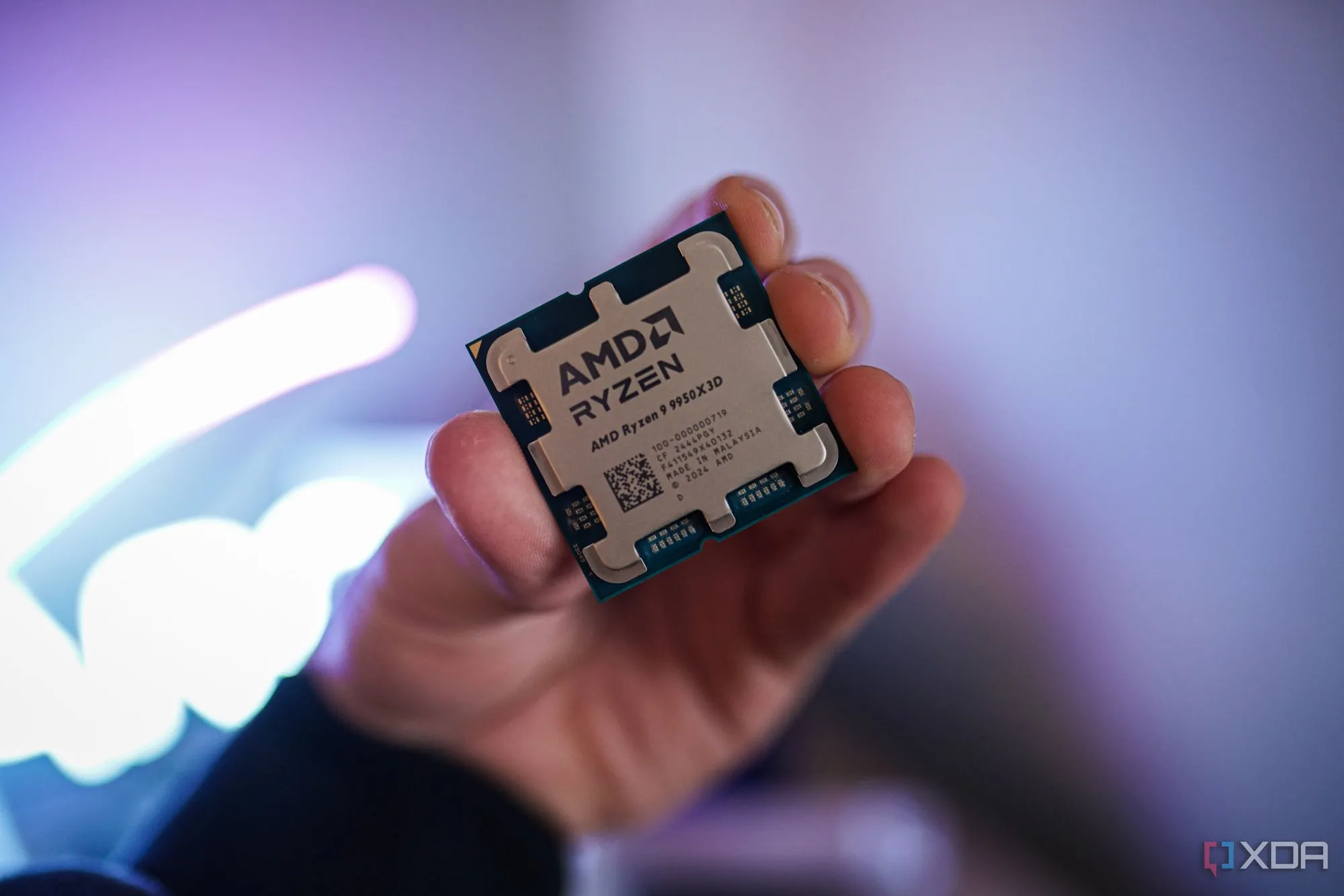 Bàn tay cầm chip CPU AMD Ryzen 9 9950X3D, hiển thị mặt trên của bộ vi xử lý
