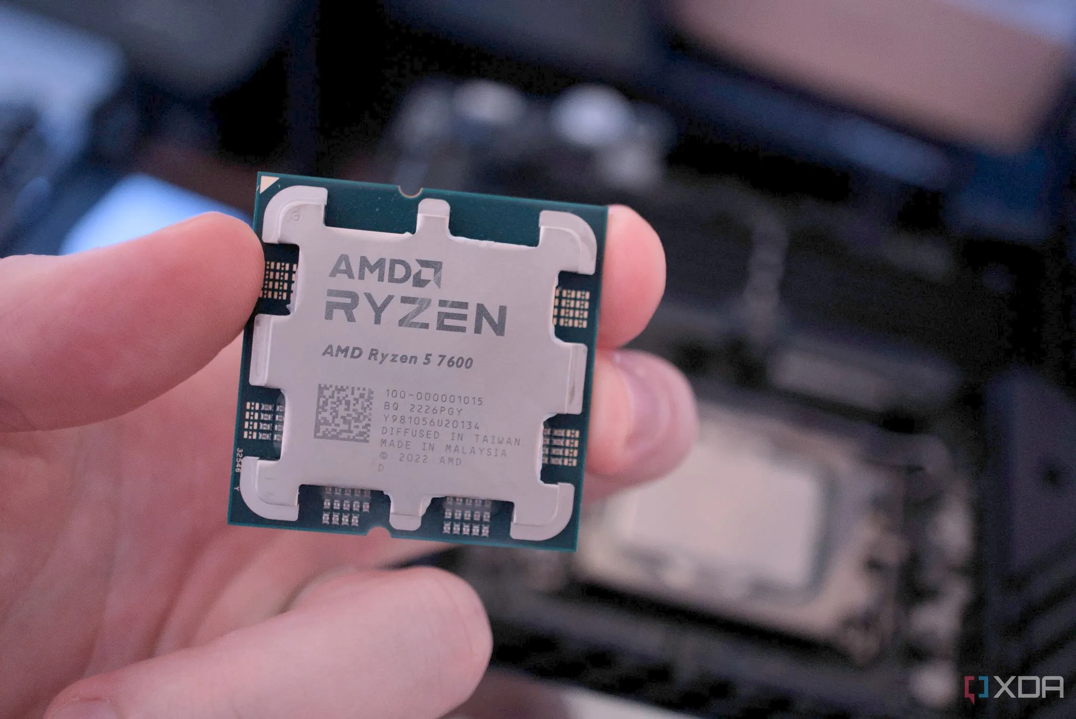 Bàn tay cầm CPU AMD Ryzen 7 7700 và CPU Intel