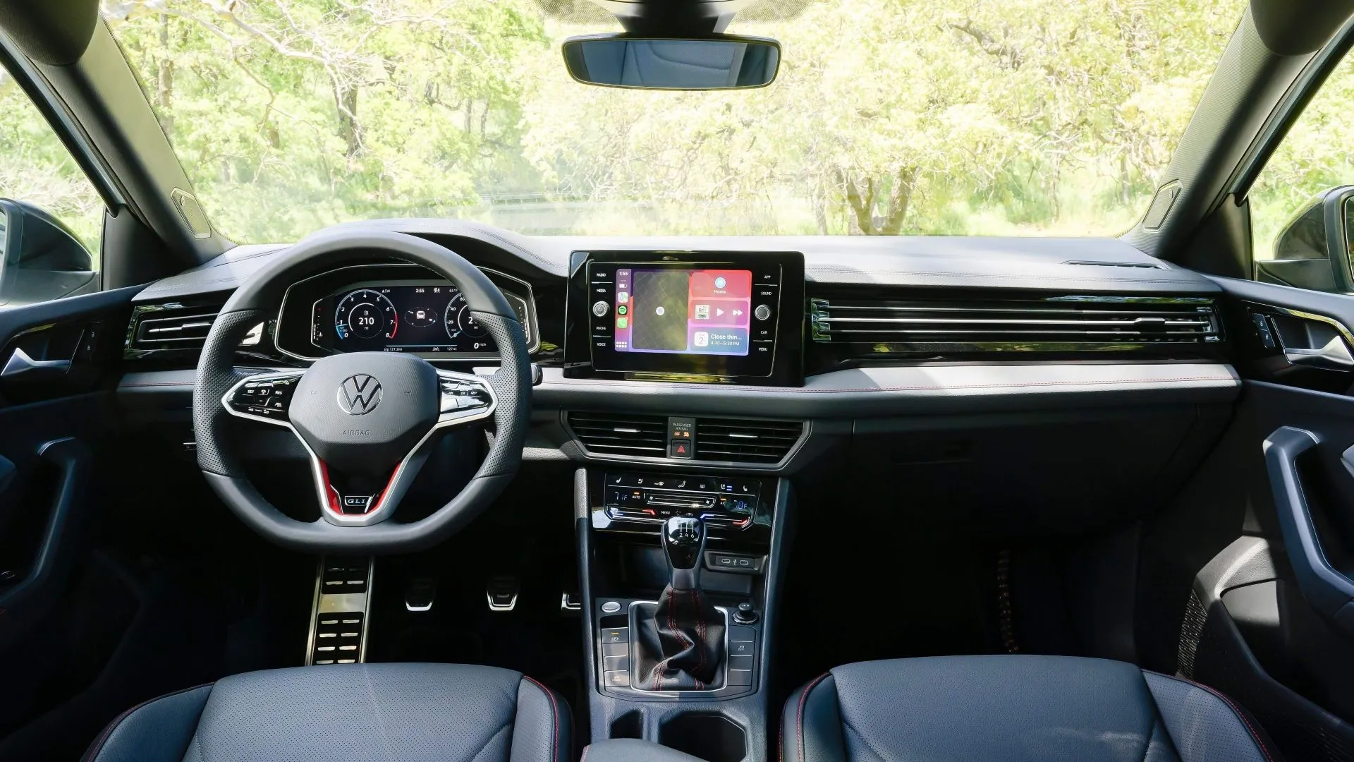 Bảng điều khiển và màn hình thông tin giải trí của Volkswagen Jetta GLI 2025 với các chi tiết màu đỏ nhấn nhá, thể hiện sự hiện đại và thể thao.
