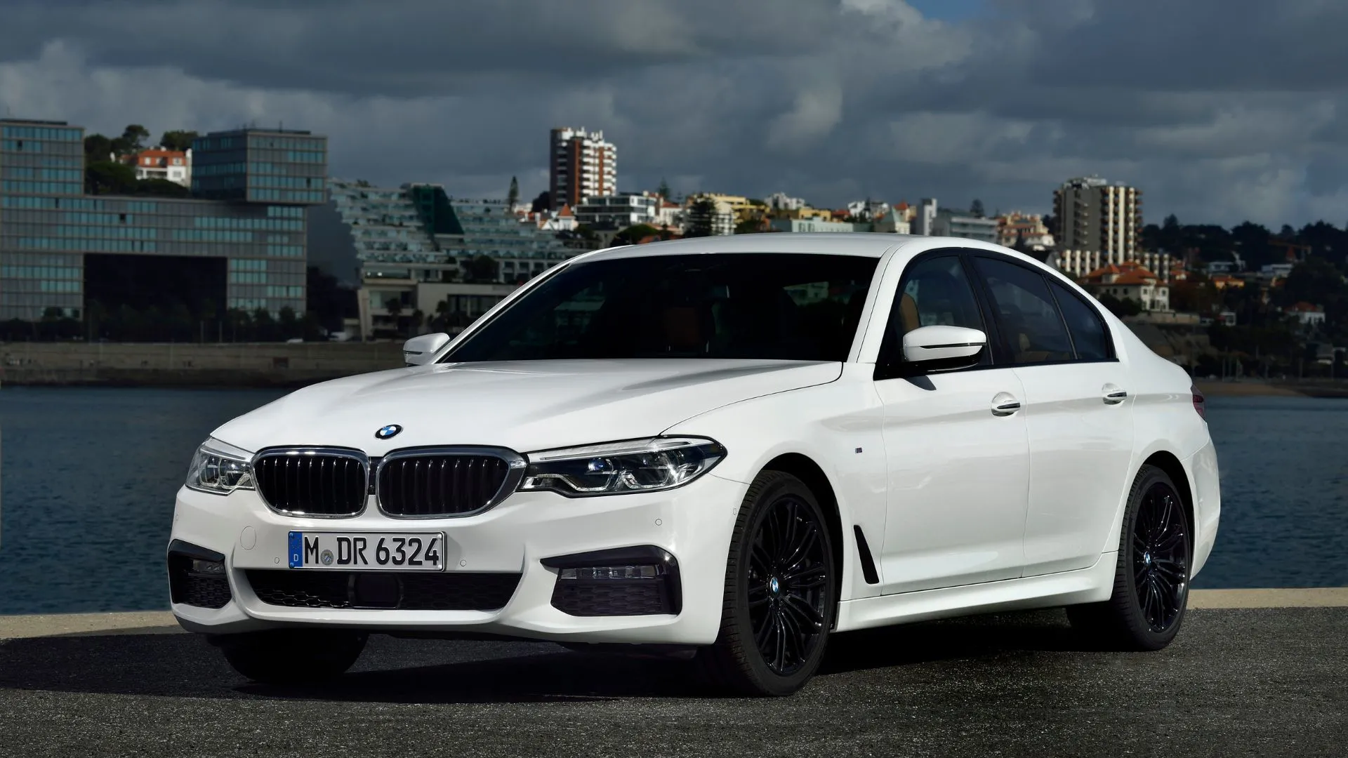 BMW 540i Sedan 2019 màu trắng đỗ trước các tòa nhà cao tầng, thể hiện sự cân bằng giữa sức mạnh động cơ sáu xi-lanh và sự tinh tế của một chiếc sedan hạng sang