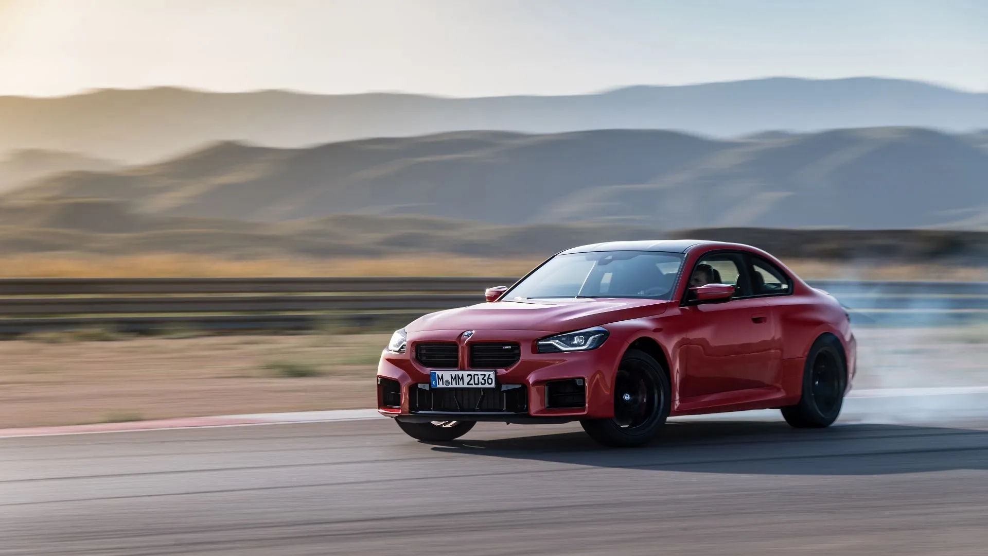 BMW M2 2025 màu đỏ đang drift trên đường