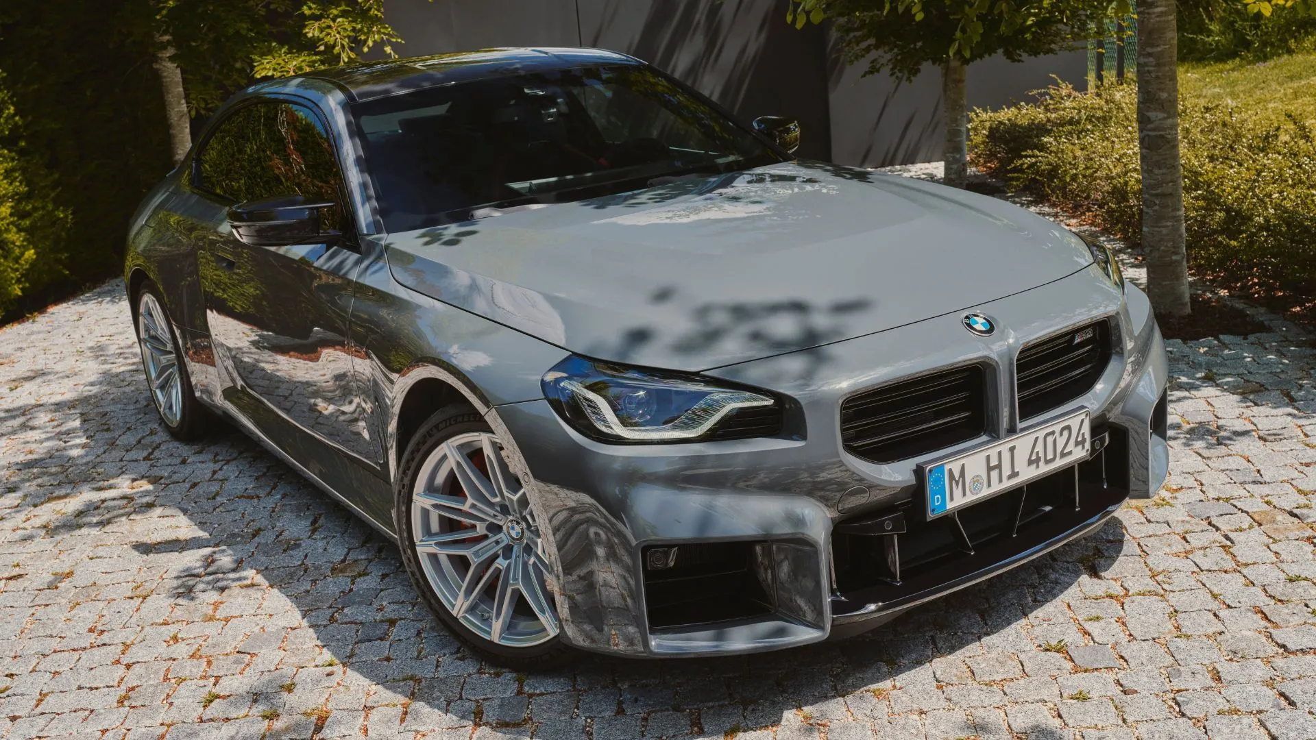 BMW M2 2025 màu xám đỗ trên đường lát đá, thể hiện phong cách thể thao và sang trọng