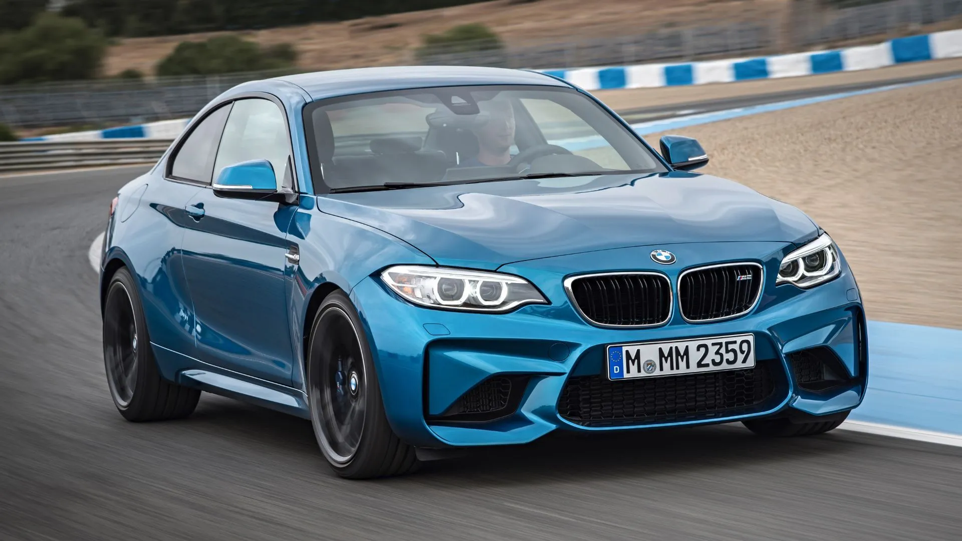 BMW M2 màu xanh dương đời 2016 trên đường đua, coupe thể thao nhỏ gọn với khả năng xử lý lái sắc bén, tập trung vào người lái.
