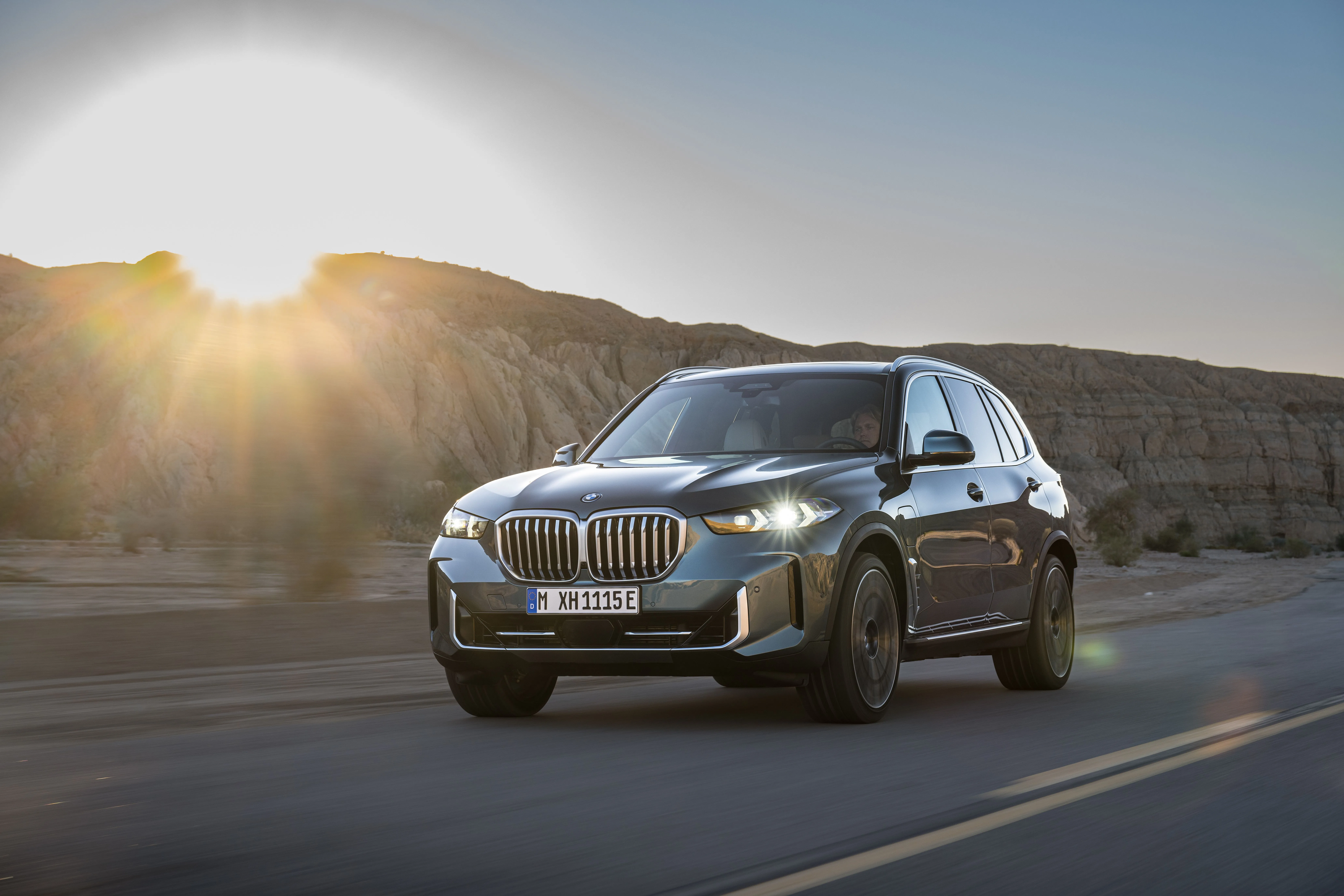 BMW X5 xDrive50e 2024 màu xanh chạy trên đường, SUV hạng sang plug-in hybrid hiệu suất cao.