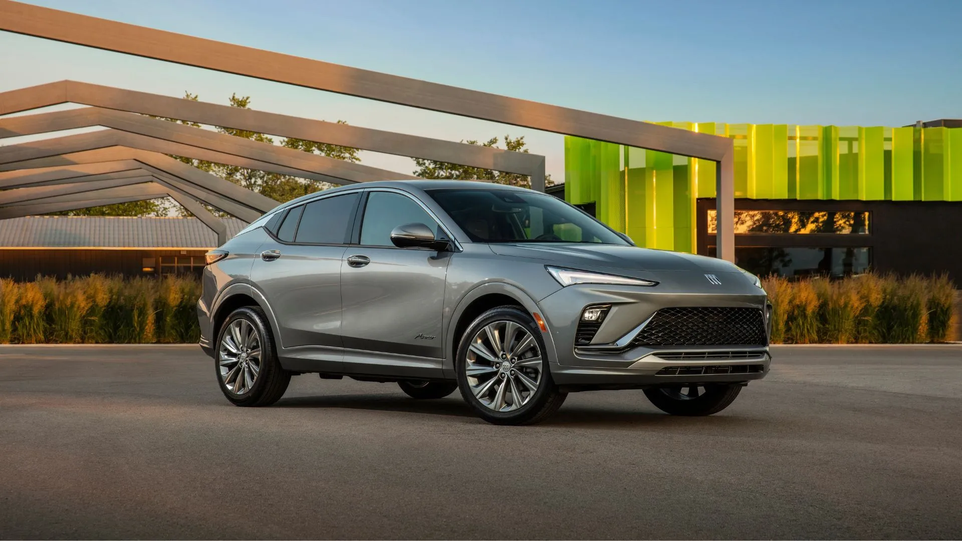 Buick Envista Avenir 2024 màu xám đỗ giữa kiến trúc hiện đại.