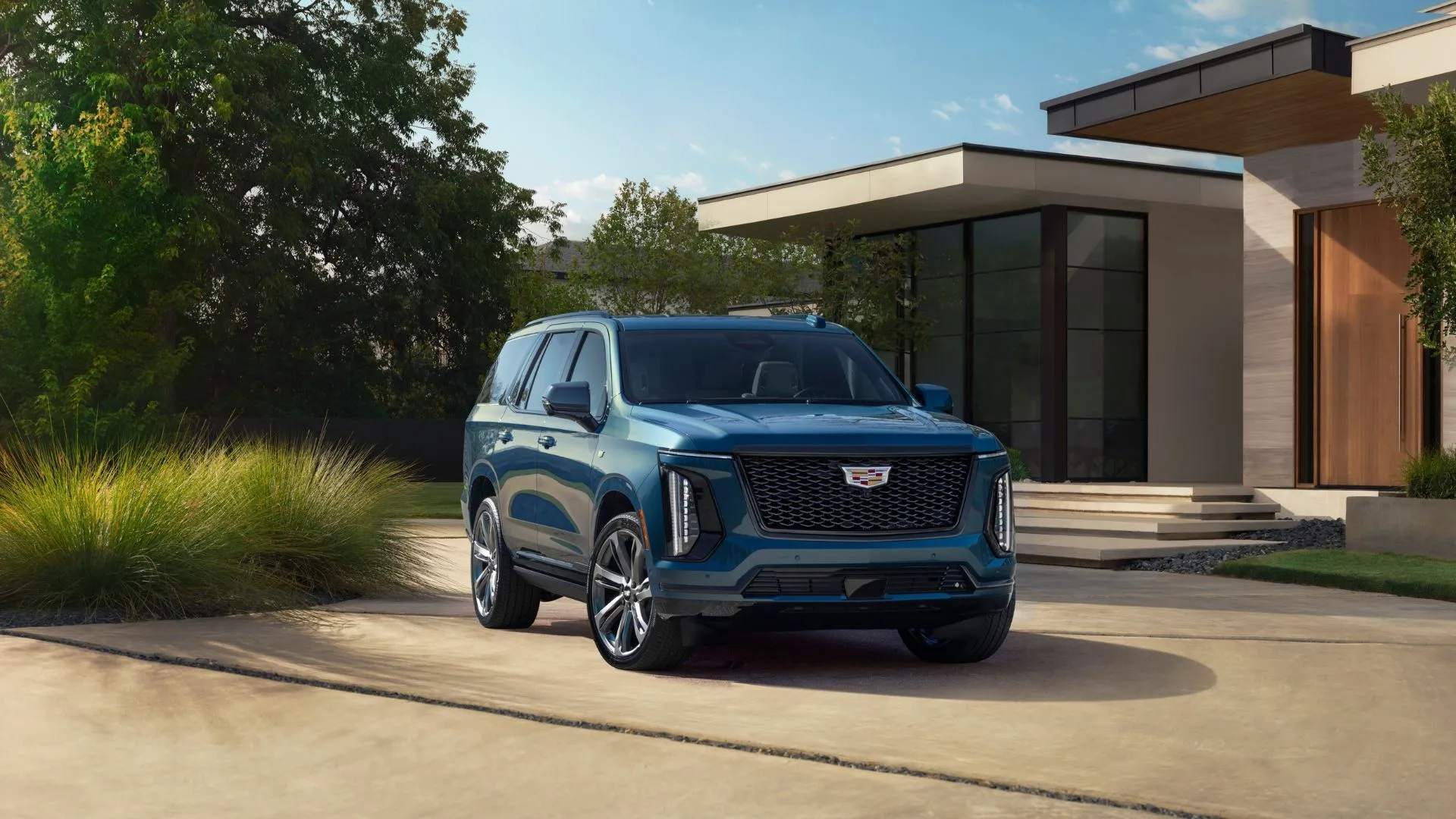 Cadillac Escalade Sport Platinum 2025 màu xanh đậm sang trọng đậu trước một ngôi nhà, mẫu SUV cỡ lớn sử dụng động cơ V8 của GM