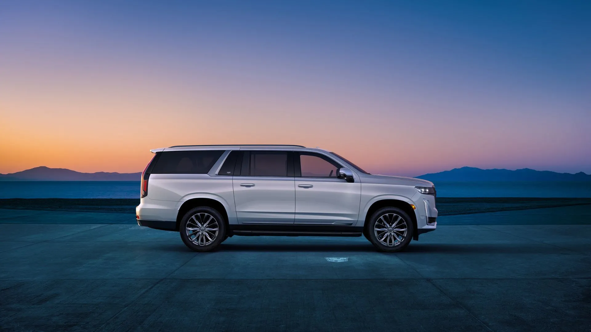 Cận cảnh Cadillac Escalade ESV 2024 màu trắng đỗ cạnh núi lúc hoàng hôn, thuộc danh sách xe GM triệu hồi.