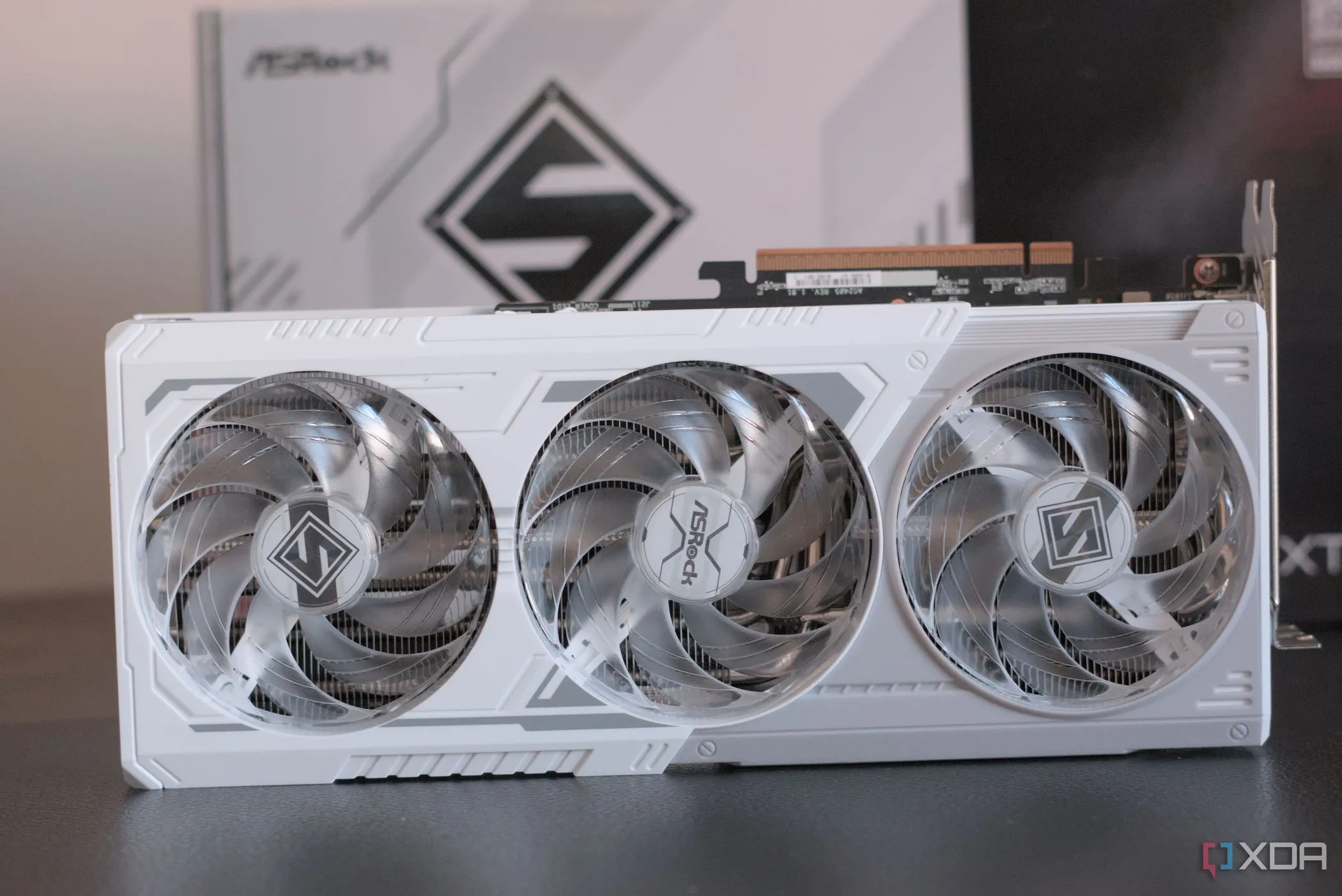 Card đồ họa ASRock Radeon RX 9070 XT Steel Legend được đặt trước hộp sản phẩm, thể hiện thiết kế và bao bì