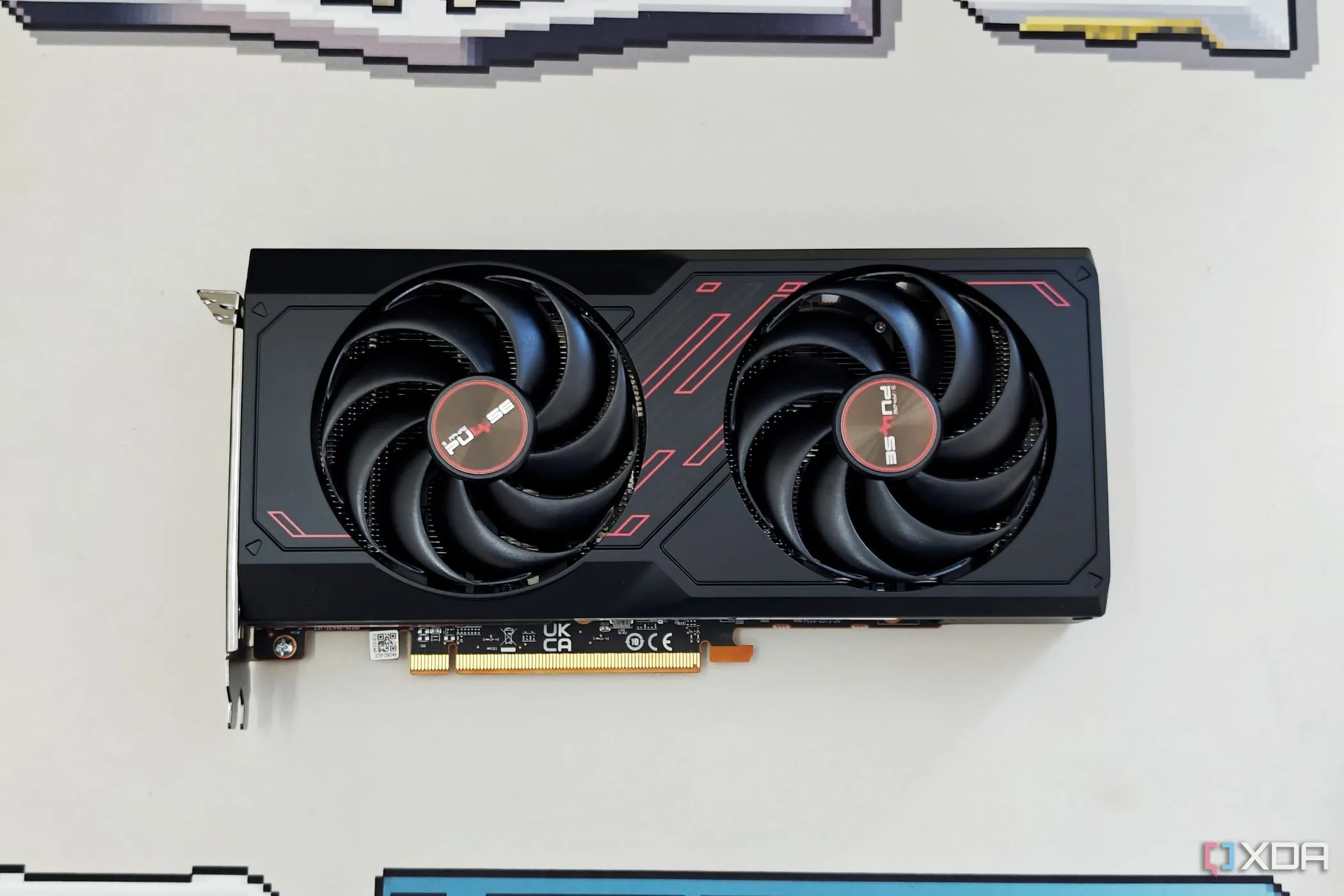 Card đồ họa Sapphire Radeon RX 7600 Pulse OC đặt trên bàn làm việc màu be, một đối thủ của Arc B580