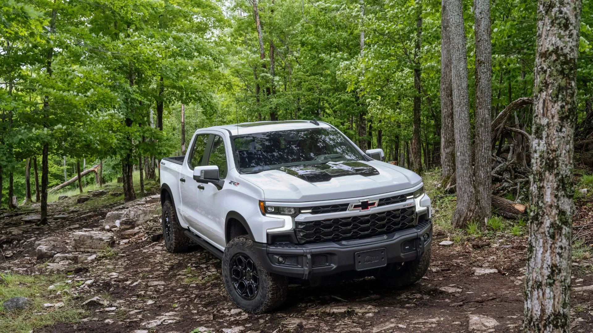 Chevrolet Silverado ZR2 2024 màu trắng đang chạy off-road trong địa hình gồ ghề, thể hiện sự mạnh mẽ của dòng xe bán tải GM
