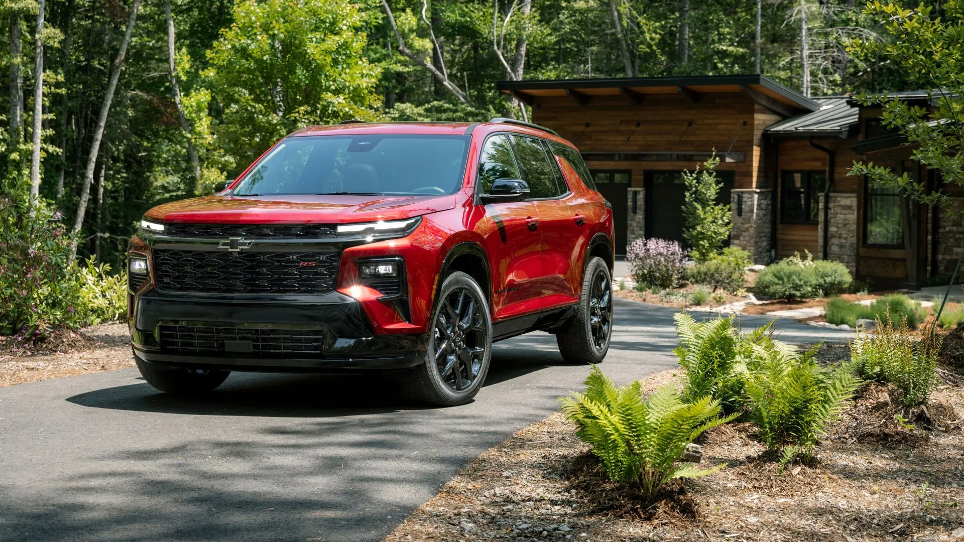 Chevrolet Traverse 2024 màu đỏ đỗ trên đường lái xe, mẫu SUV 3 hàng ghế đáng tin cậy.