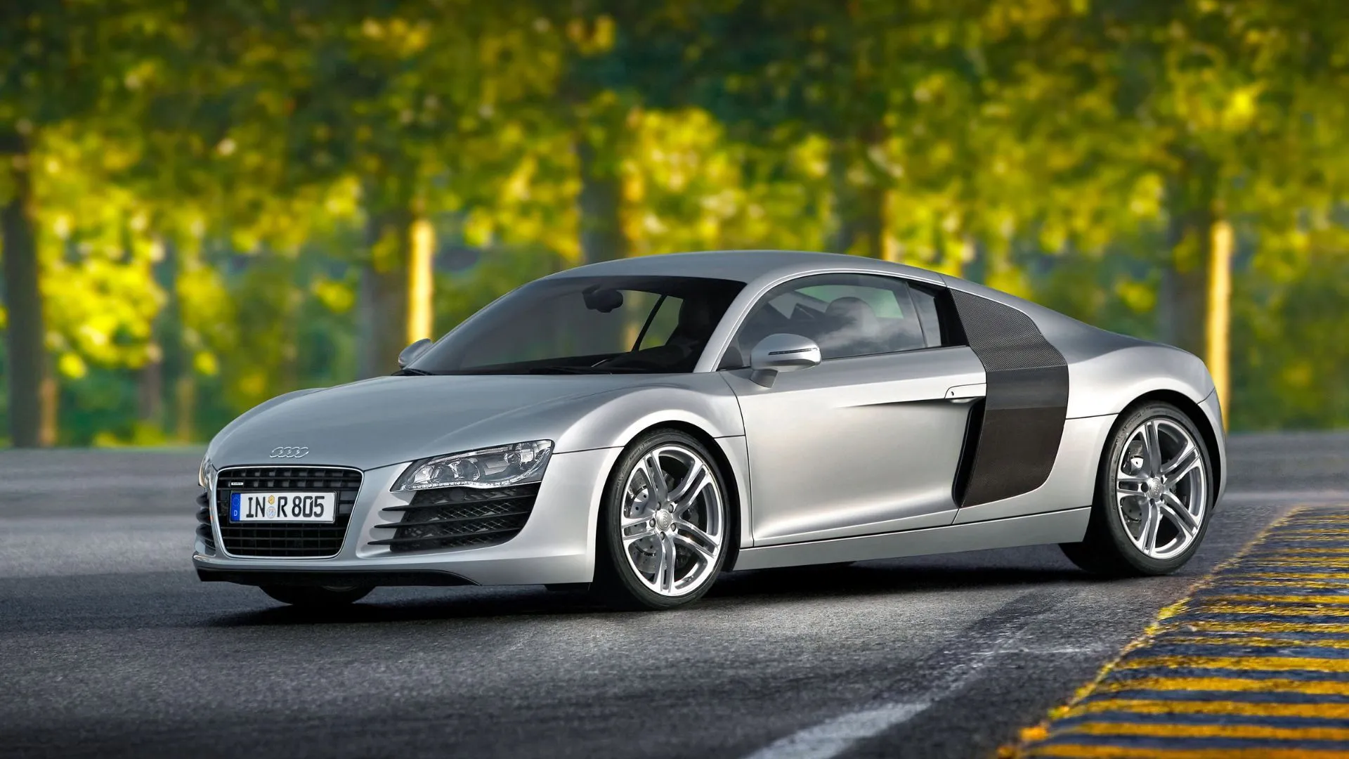 Chiếc Audi R8 V8 màu bạc đậu ngang trên đường đua, phô diễn thiết kế ngoại thất độc đáo và hiệu suất cao.