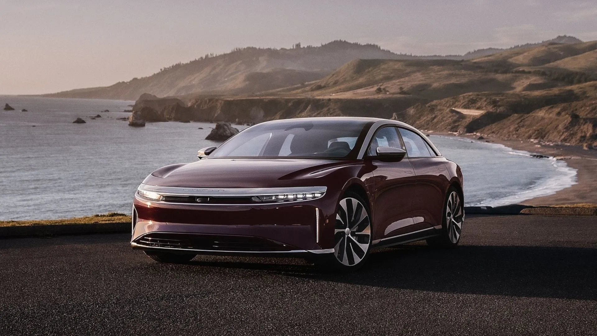 Chiếc Lucid Air Touring màu bạc đang lái trên đường cao tốc với phong cảnh sa mạc hùng vĩ.