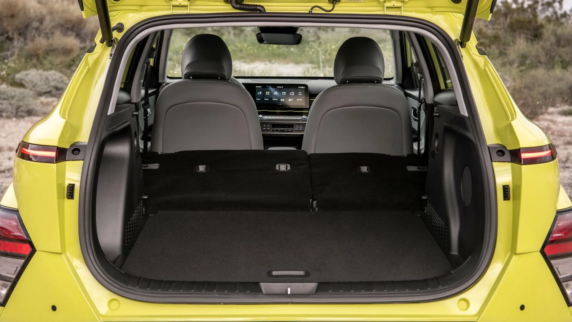 Chụp cận cảnh bên trong khoang hành lý của một chiếc Hyundai Kona Electric 2025 màu vàng.