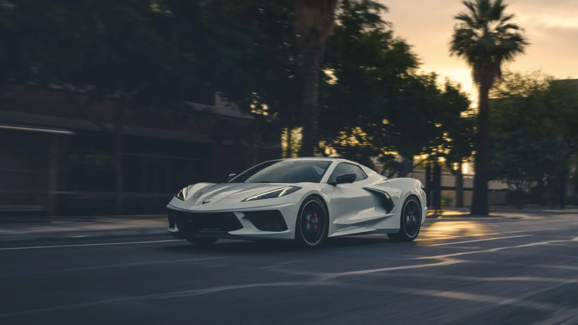 Corvette Stingray 2025 màu trắng lái trong thành phố lúc hoàng hôn, siêu xe thể thao Mỹ với độ bền ấn tượng.