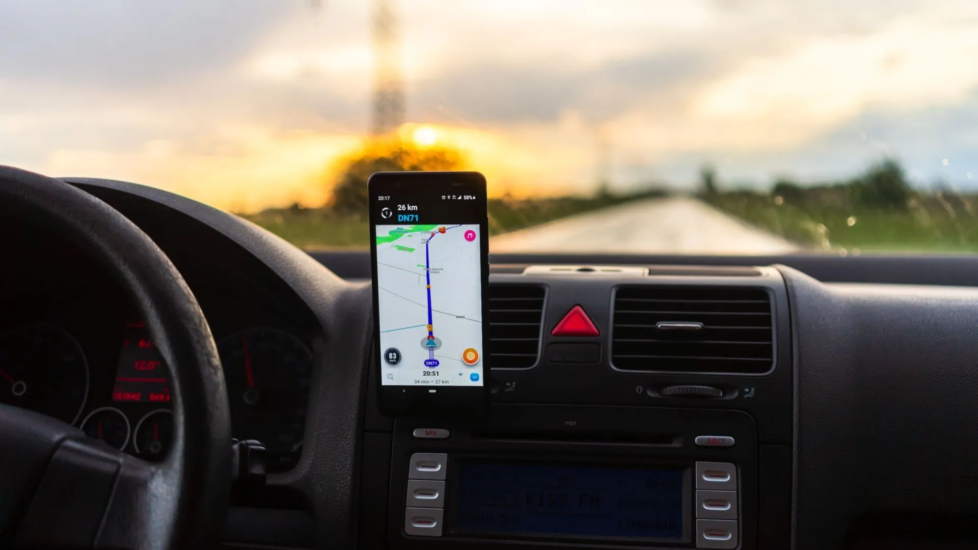 Điện thoại Android trong giá đỡ trên bảng điều khiển ô tô, hiển thị ứng dụng điều hướng.