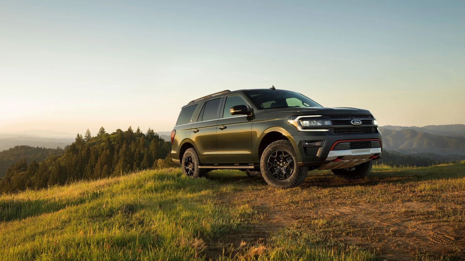 Ford Expedition 2023 màu xanh lá cây đỗ trên cỏ ở vùng nông thôn, nhấn mạnh không gian rộng rãi và khả năng kéo vượt trội của mẫu SUV 3 hàng ghế cũ.