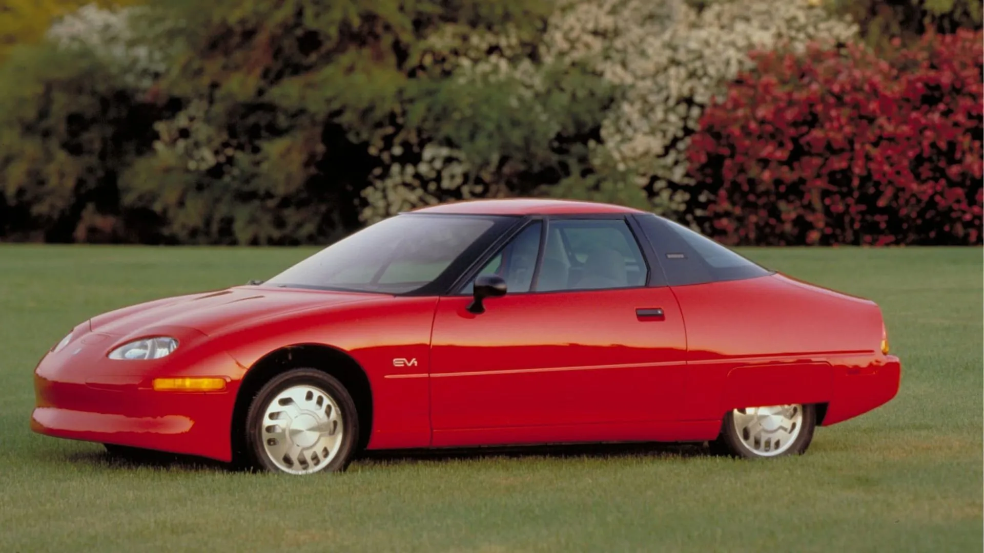 General Motors EV1 màu đỏ đời 1996, tiên phong xe điện với phanh tái sinh và sạc cảm ứng.