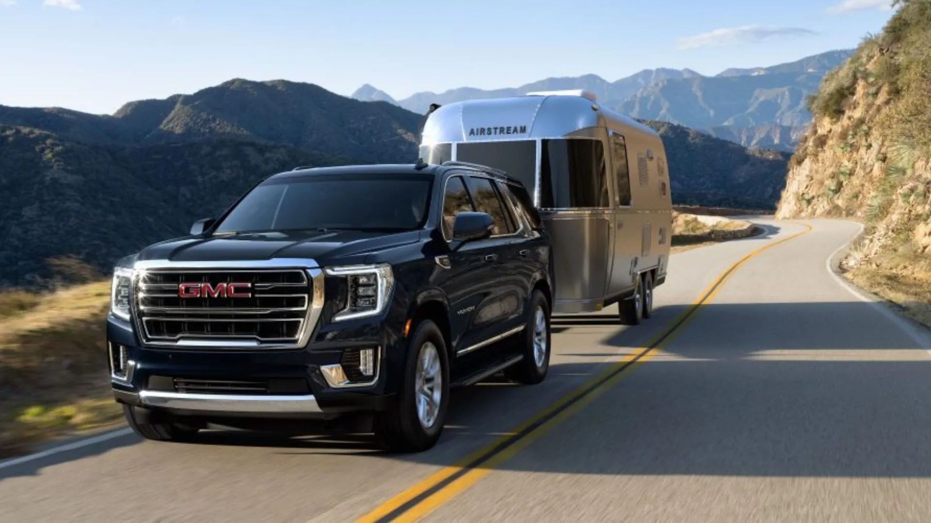 GMC Yukon 2022 màu đen kéo rơ-moóc trên đường núi, thể hiện khả năng kéo ấn tượng của SUV cũ cỡ lớn.