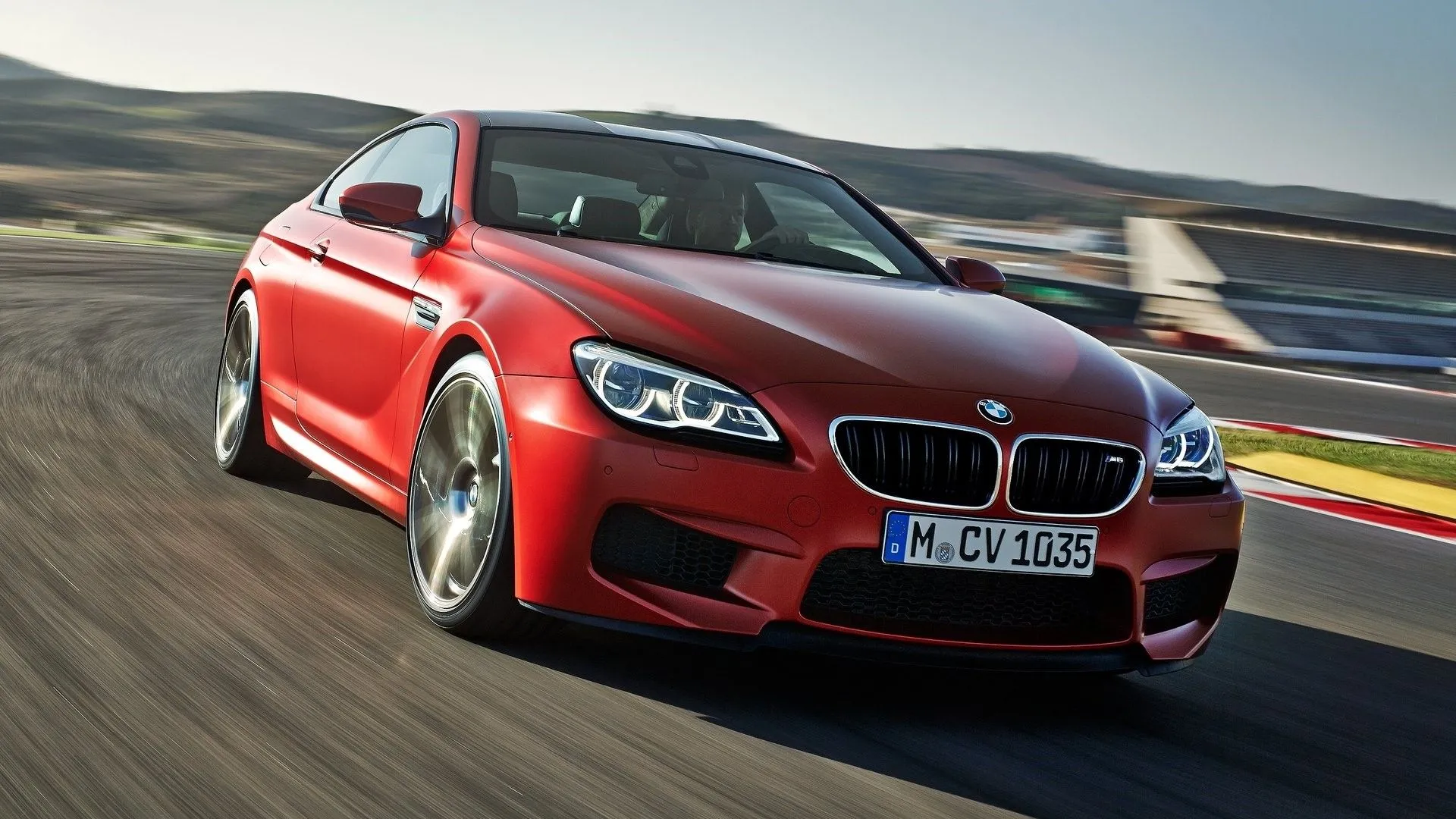 Góc 3/4 phía trước của BMW M6 2015 màu trắng đang phóng nhanh trên đường