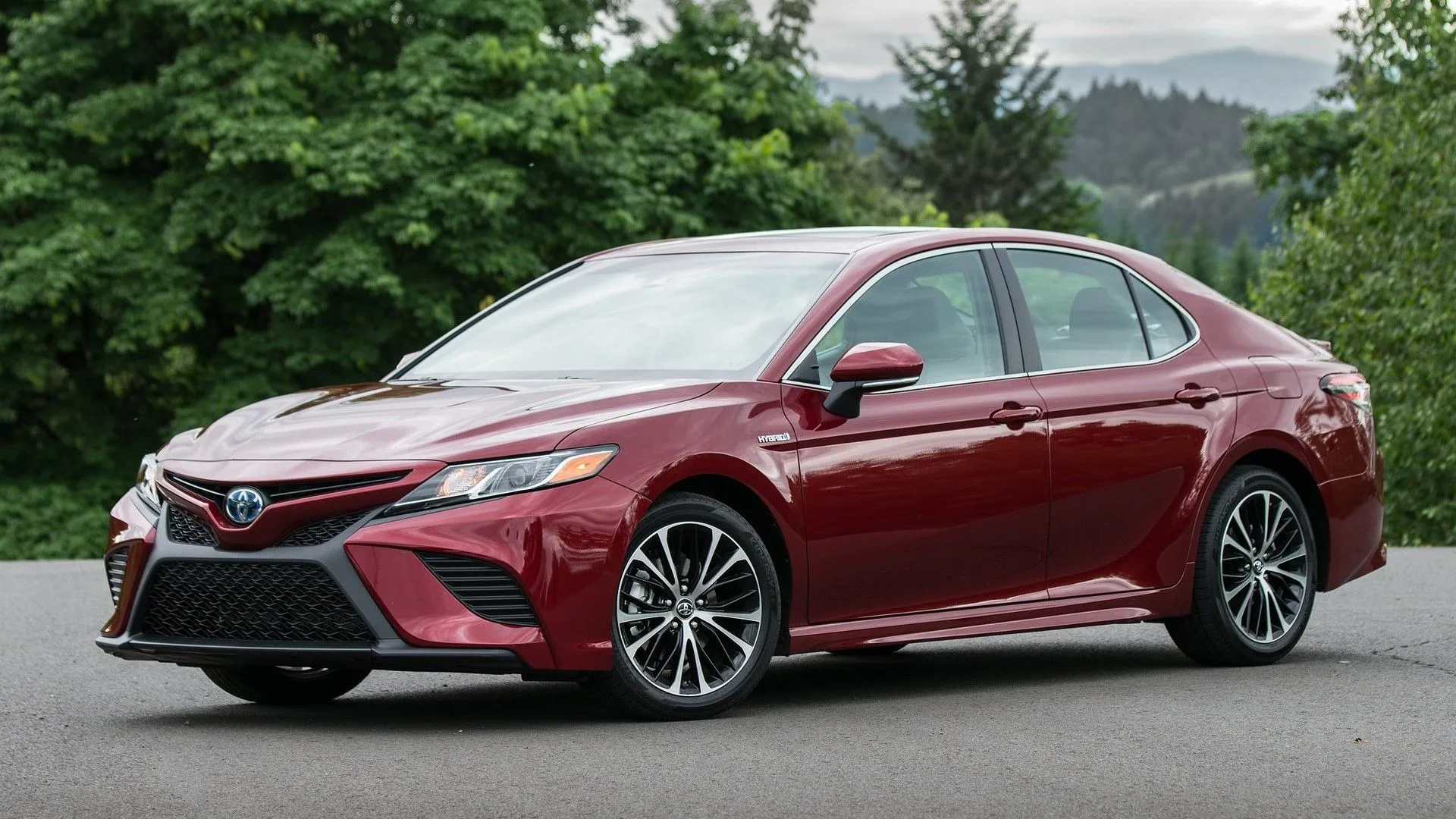 Góc 3/4 phía trước của Toyota Camry 2018 màu bạc, với thiết kế sắc sảo và lưới tản nhiệt lớn.
