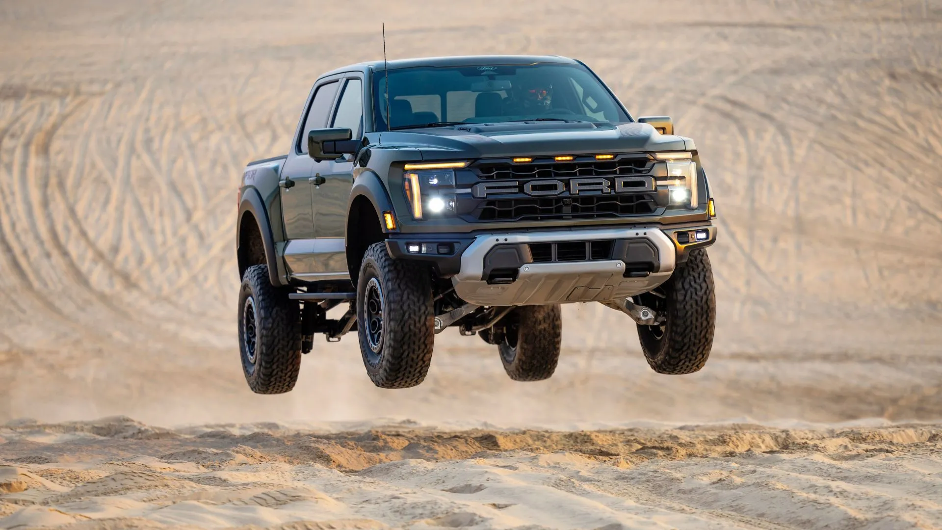 Góc ba phần tư phía trước của Ford F-150 Raptor 2024 đang bay lên trong cồn cát, thể hiện sức mạnh và khả năng off-road vượt trội.