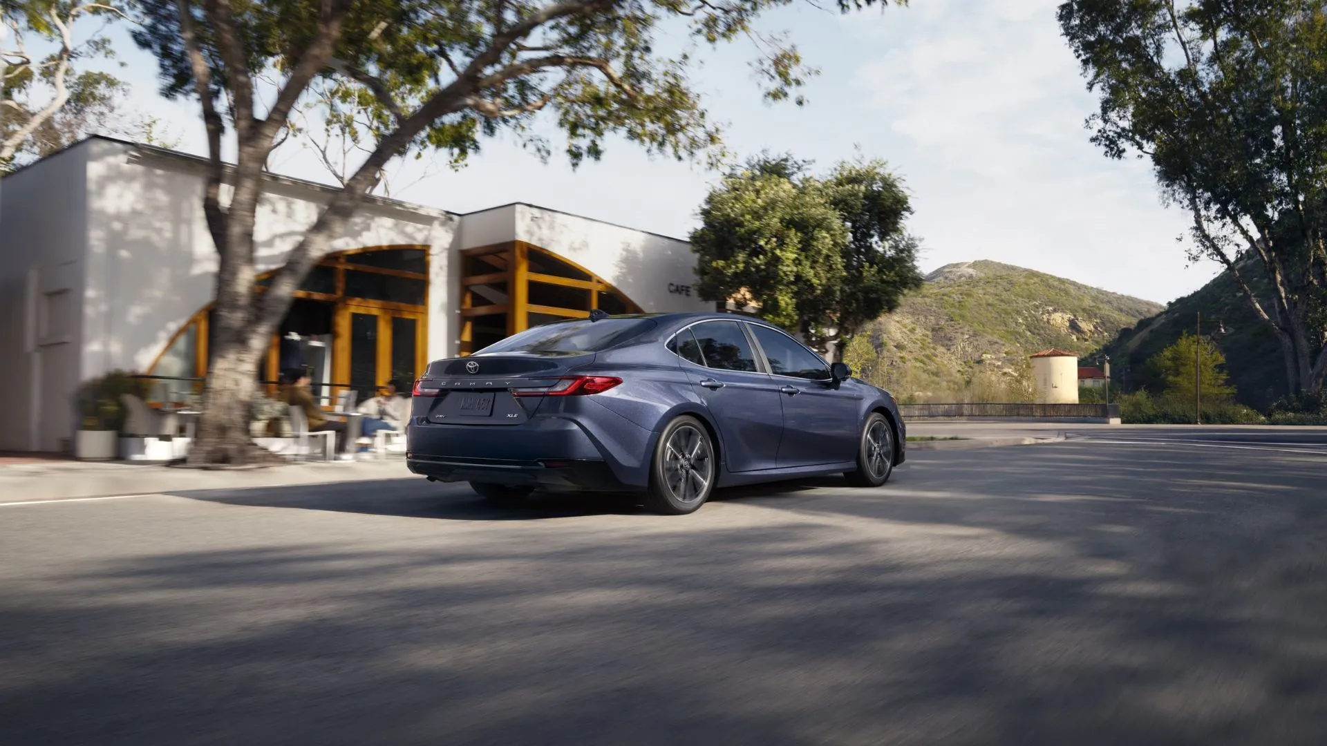 Góc nhìn phía sau của Toyota Camry 2026 màu xám trên đường phố, làm nổi bật thiết kế khí động học và cụm đèn hậu