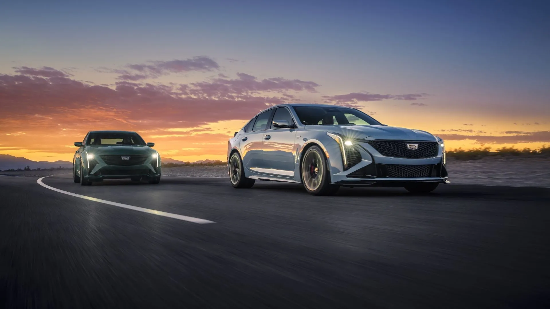 Hai mẫu xe Cadillac CT5-V và CT5-V Blackwing đời 2025 đang chạy trên đường đua, nổi bật với thiết kế thể thao mạnh mẽ và hiệu suất cao.