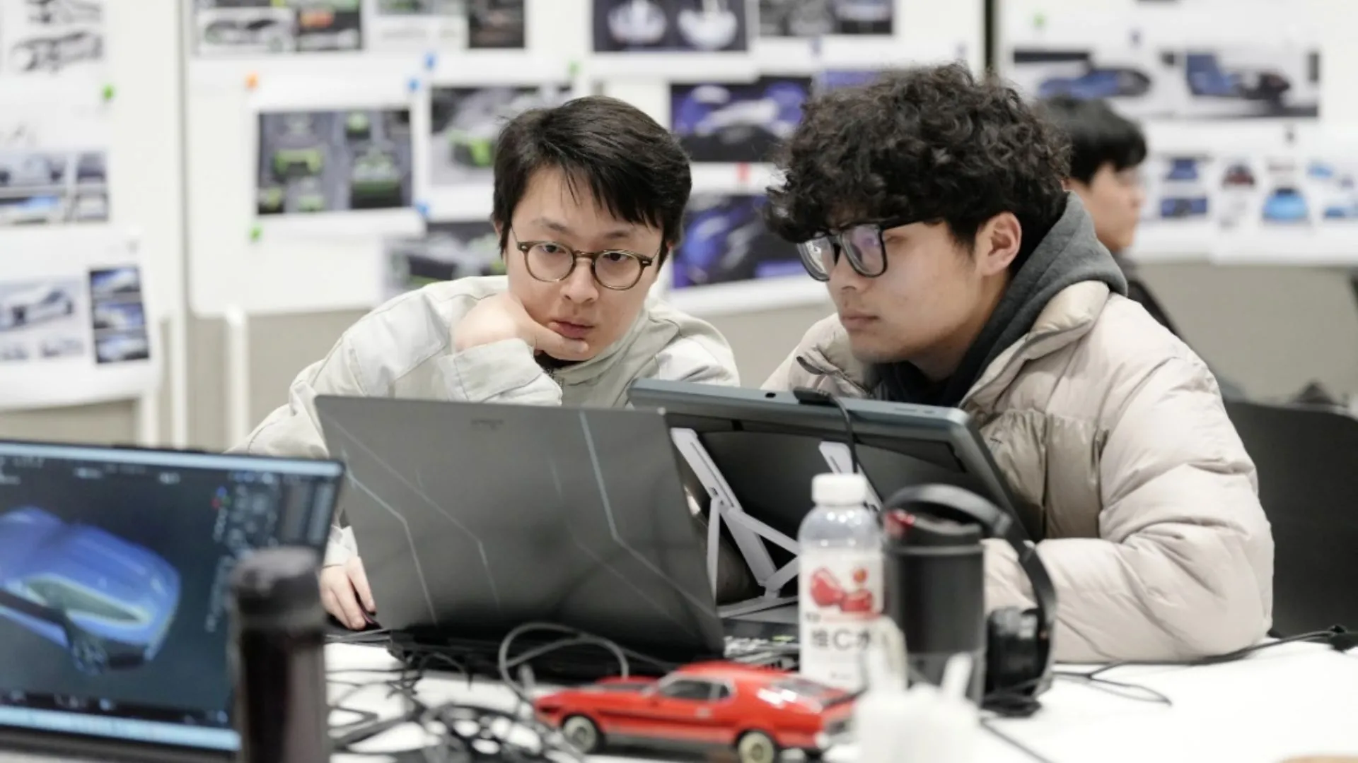 Hai sinh viên tài năng đang làm việc với thiết kế concept Ford Mustang trên laptop tại trung tâm thiết kế của Ford, sử dụng công cụ VR hiện đại.