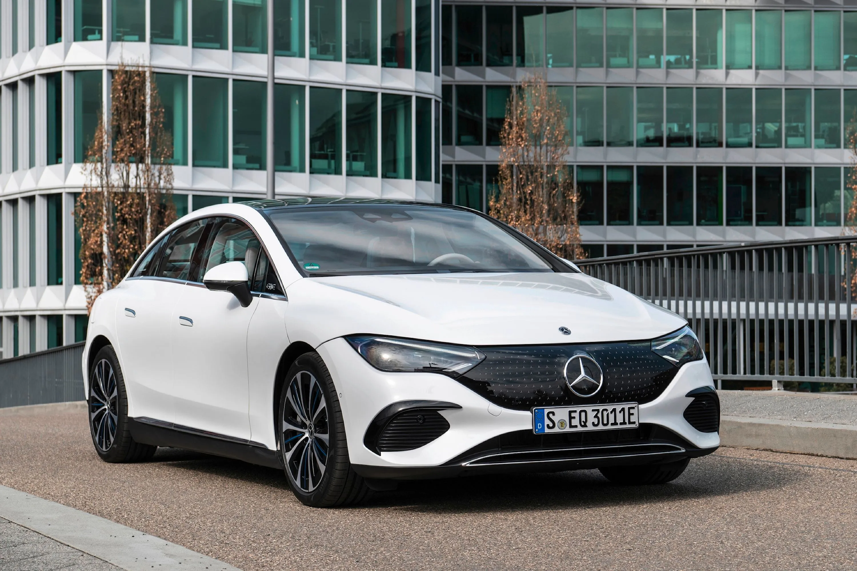 Hình ảnh chiếc Mercedes-Benz EQE Sedan màu trắng bạc đang đỗ bên đường.