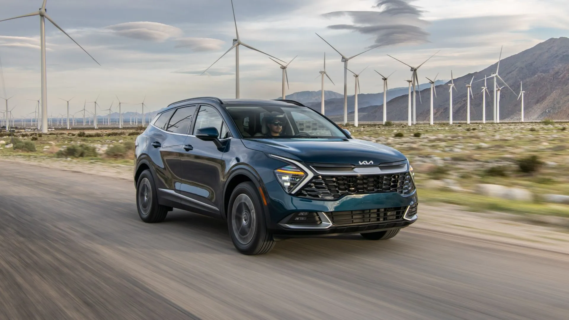 Hình ảnh góc ba phần tư phía trước của chiếc Kia Sportage hybrid 2025 màu trắng đang di chuyển trên đường.