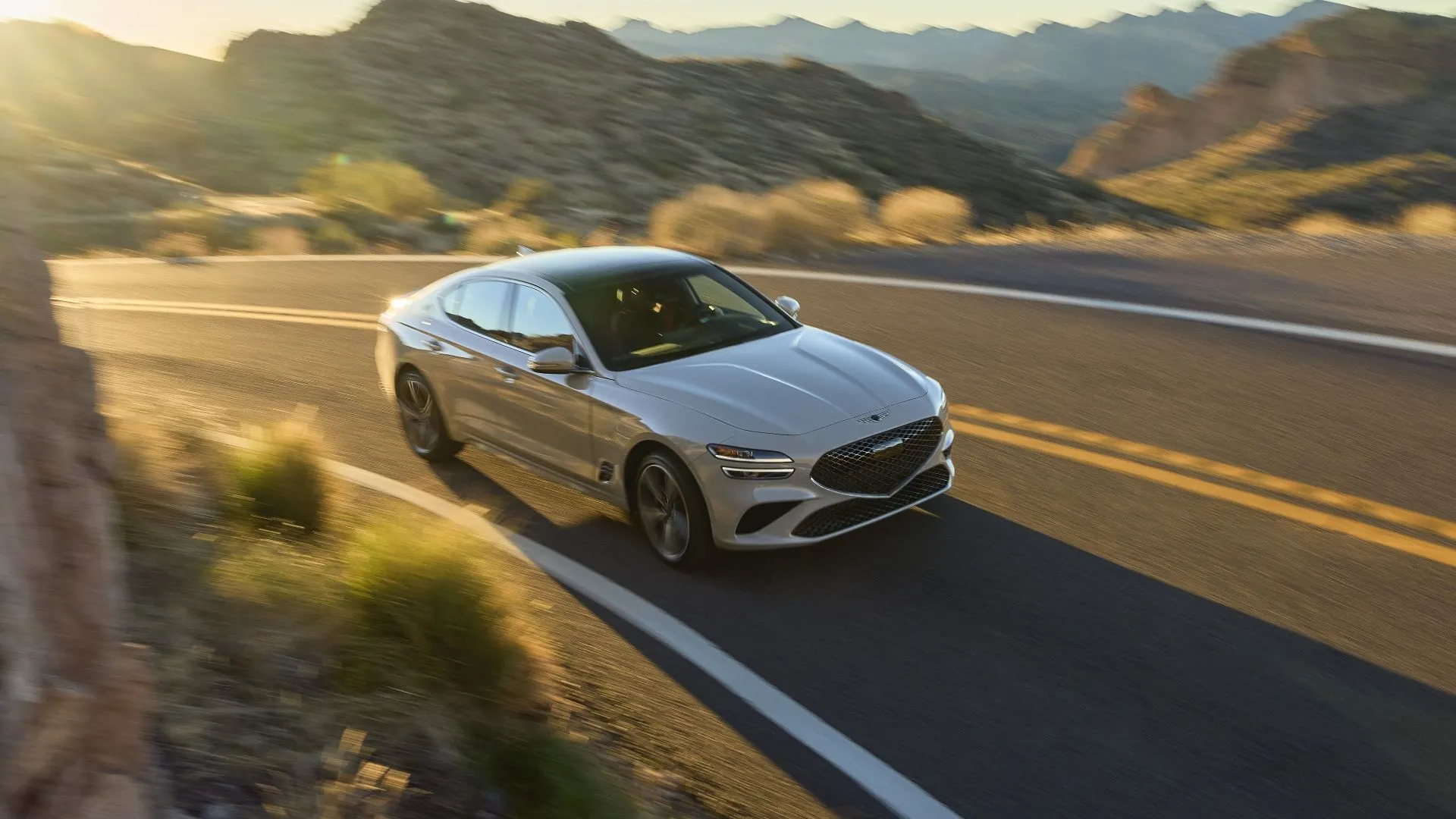Hình ảnh hoạt động góc 3/4 phía trước của Genesis G70 2025 màu xám trên đường