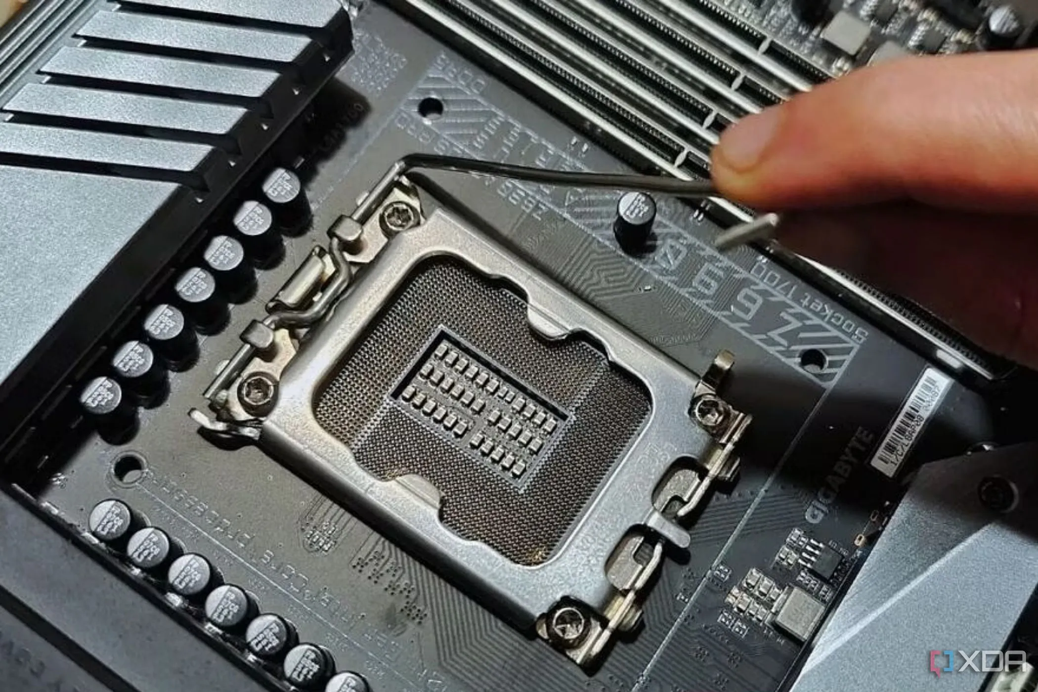 Hình ảnh một người đang giữ cần gạt kim loại nằm cạnh socket CPU