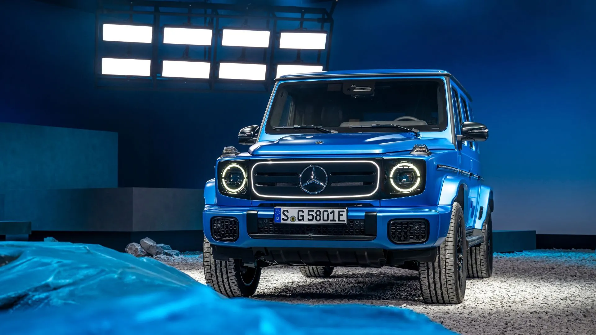 Hình ảnh tĩnh góc 3/4 phía trước của Mercedes-Benz G580 EQ màu xanh dương trong phòng studio.