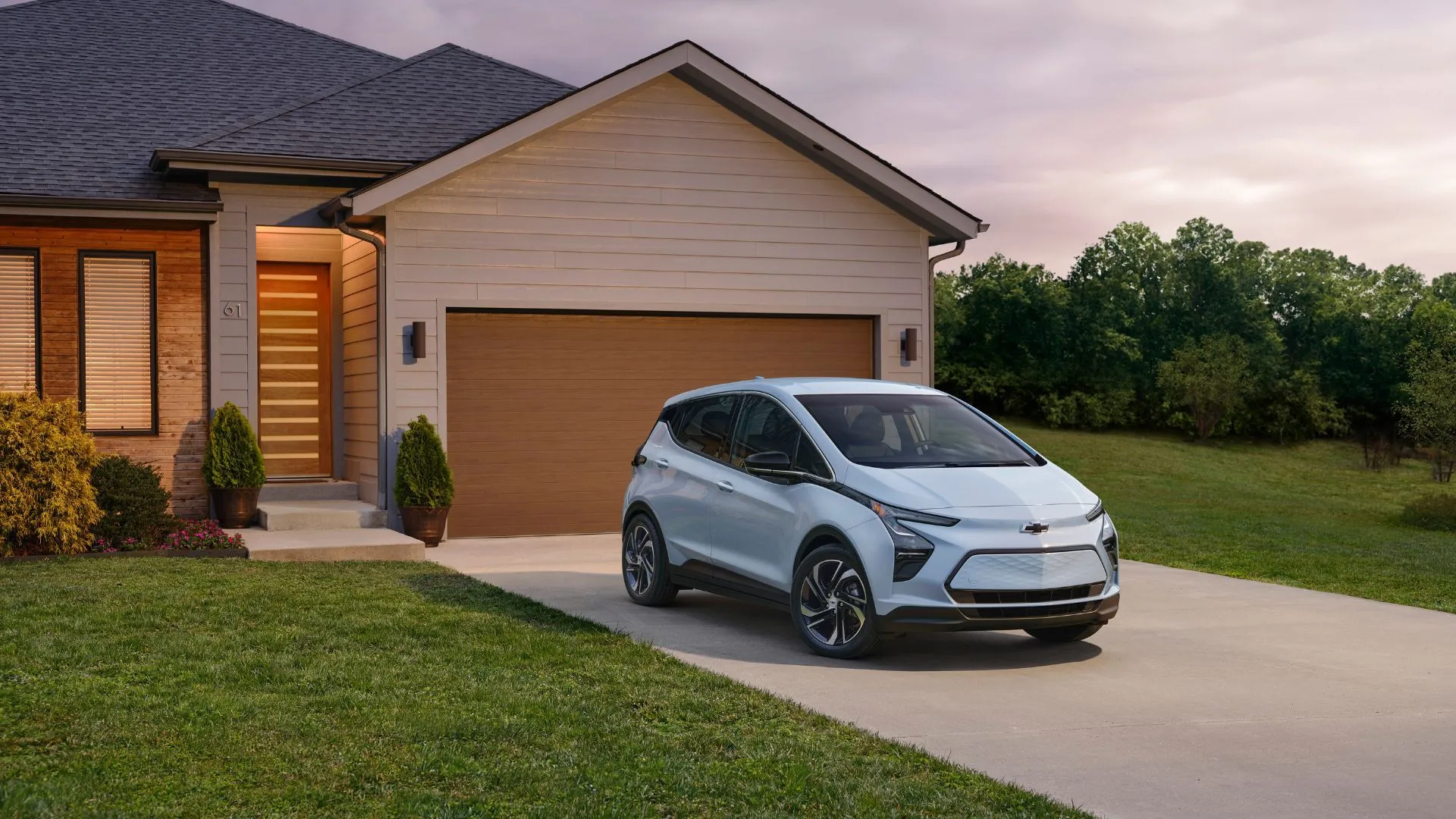 Hình ảnh tĩnh xe Chevrolet Bolt EV 2023 màu xanh nhạt đậu trước nhà, thể hiện thiết kế thanh lịch, gọn gàng và phù hợp với cuộc sống đô thị của mẫu xe điện hatchback này.