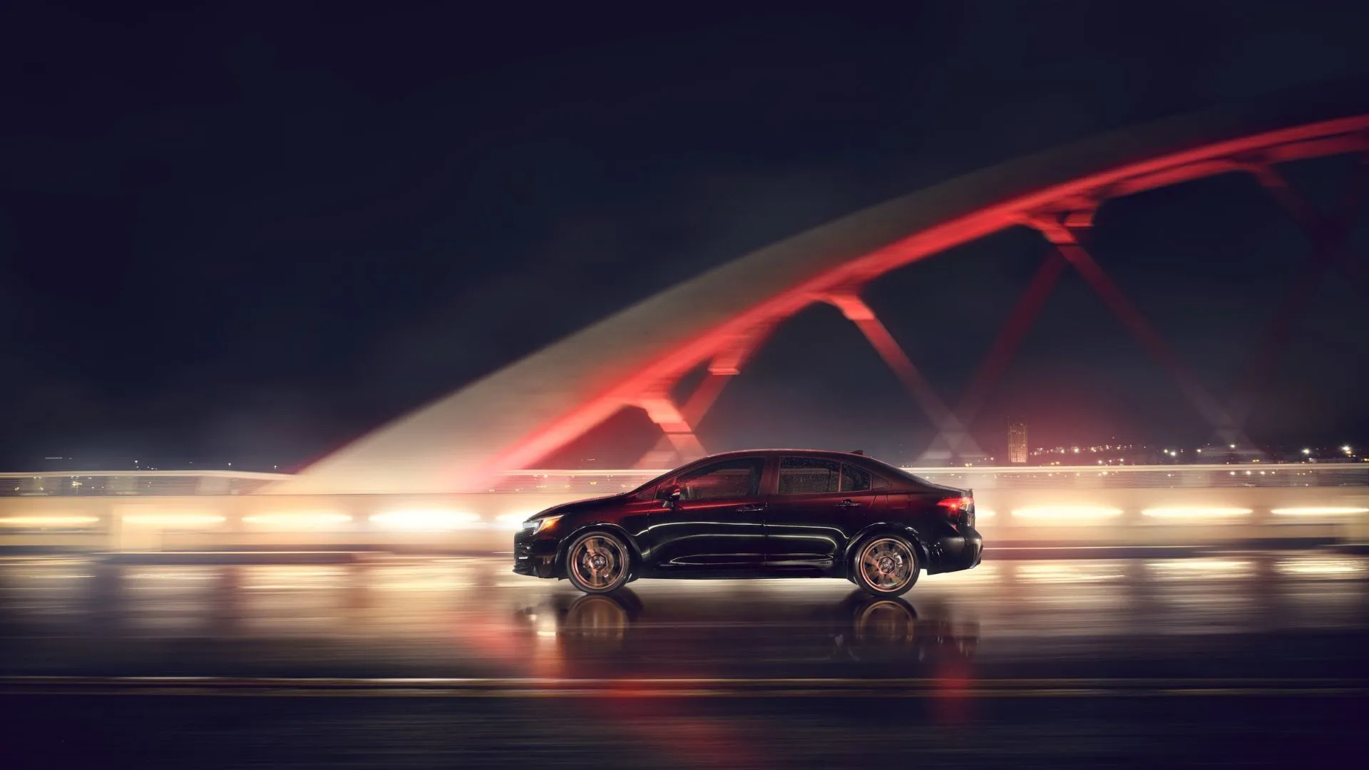 Hình ảnh Toyota Corolla Nightshade 2024 màu đen di chuyển trên cầu vào ban đêm, tượng trưng cho độ bền và khả năng giữ giá vượt trội của dòng xe Corolla.