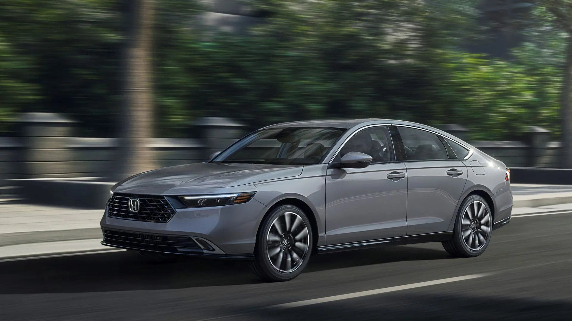Honda Accord Touring 2025 màu xám đang di chuyển trên đường phố đông đúc.