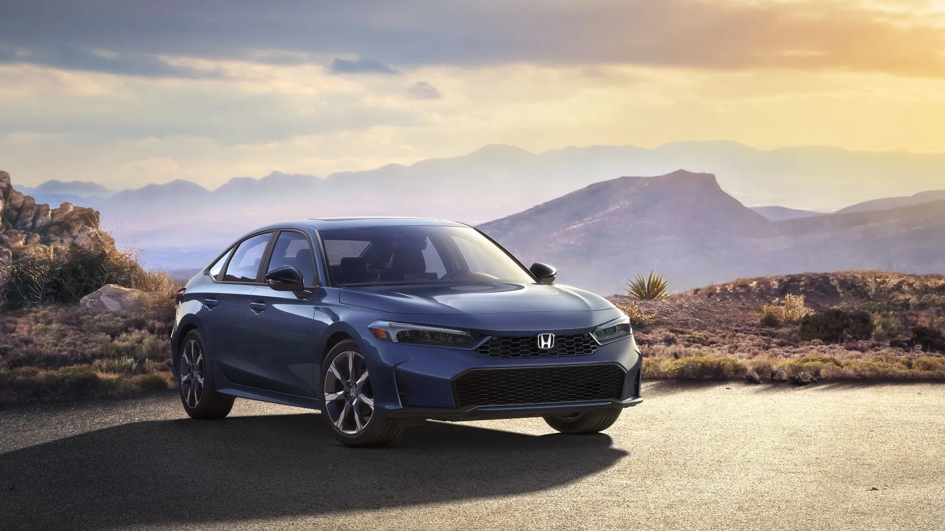 Honda Civic Sedan Sport Touring Hybrid 2025 màu xám đỗ trên đường nhựa với cảnh núi non