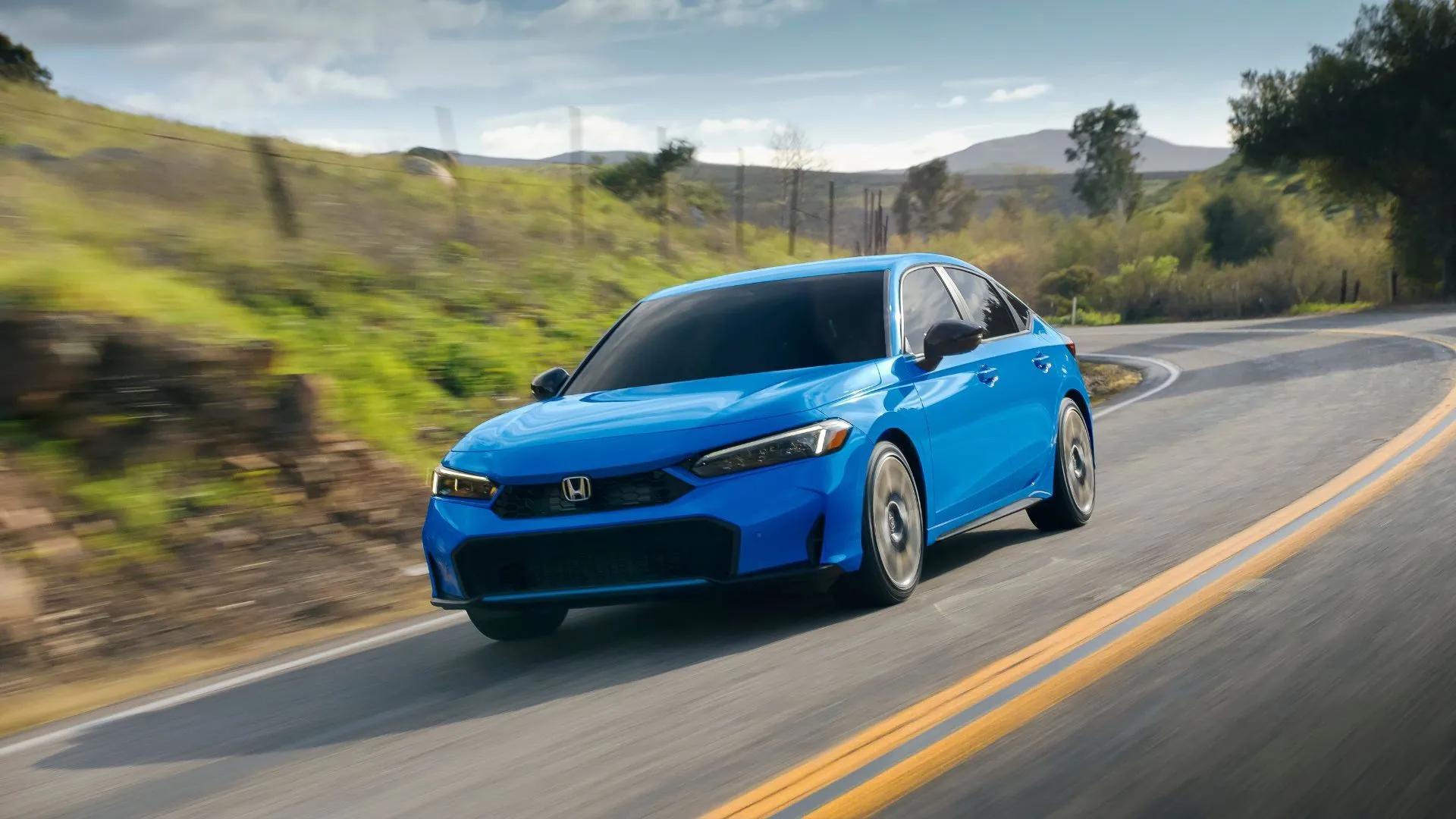 Honda Civic Touring 2023 màu xanh đậm đang di chuyển trên con đường nông thôn quanh co, thể hiện sự linh hoạt và các tính năng công nghệ của xe.