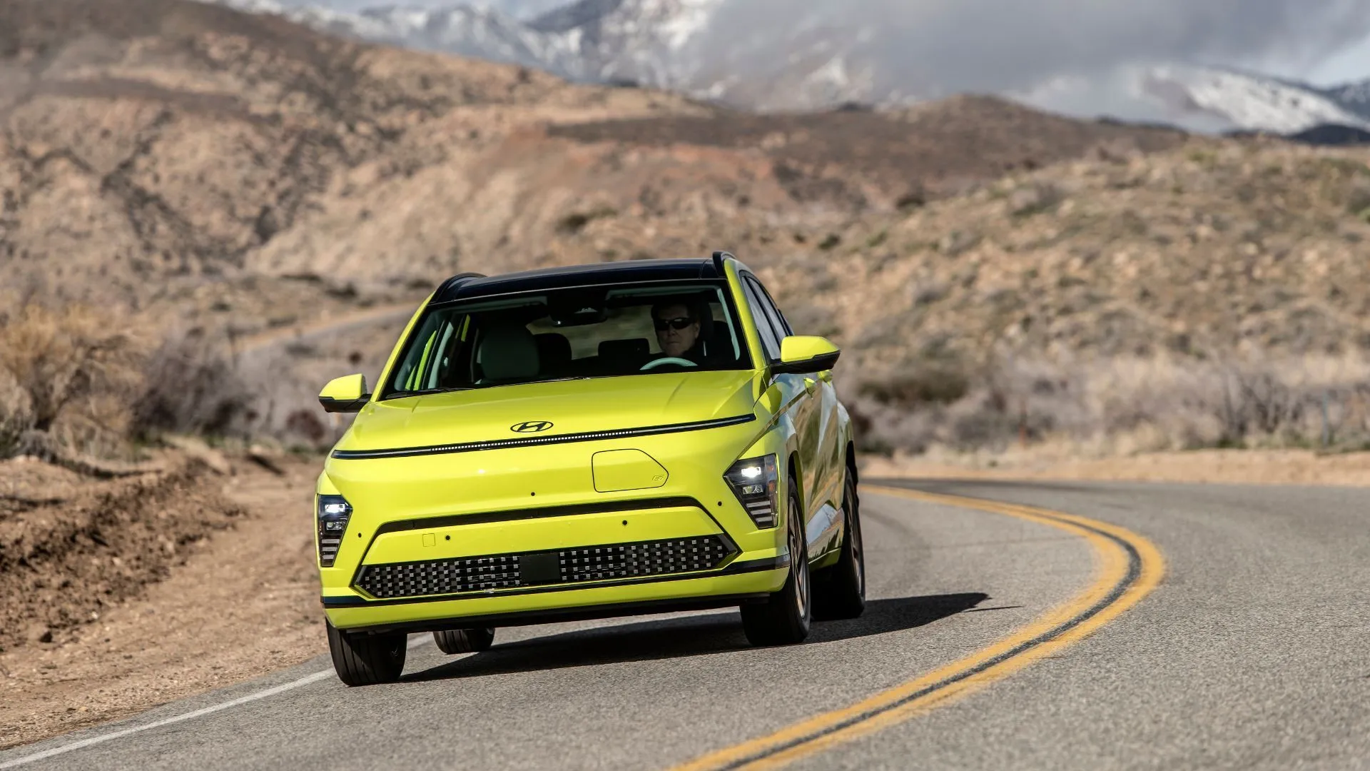 Hyundai Kona Electric 2025 màu vàng di chuyển trên đường quanh co