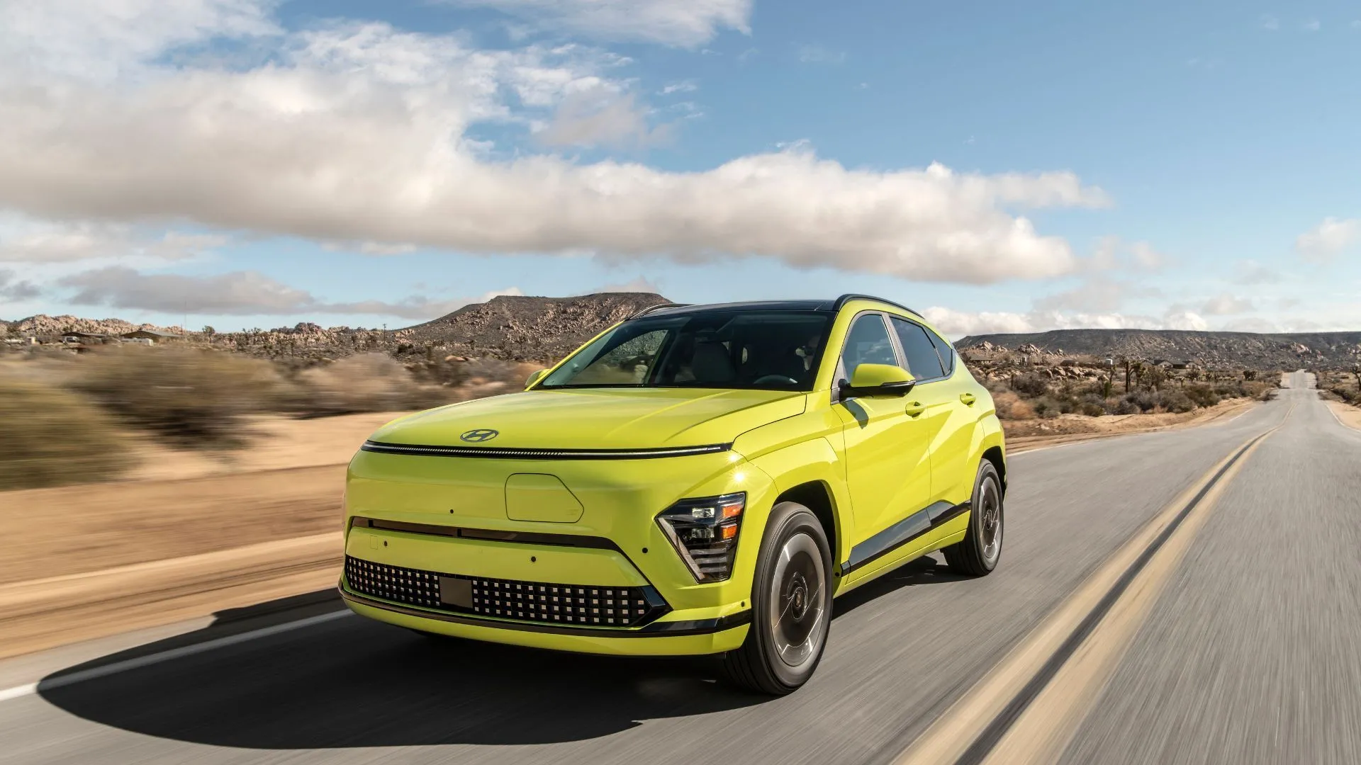 Hyundai Kona Electric 2025 màu vàng trên đường sa mạc, mẫu xe điện nhỏ gọn lý tưởng cho đô thị.