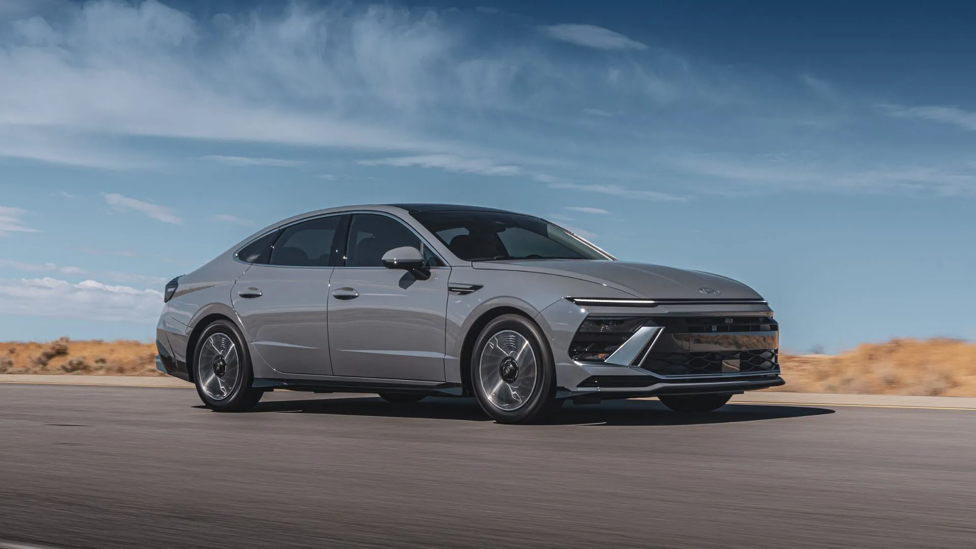 Hyundai Sonata Hybrid Limited 2025 màu xám bạc đang di chuyển trên đường quê, thể hiện vẻ ngoài sang trọng với mức giá phải chăng