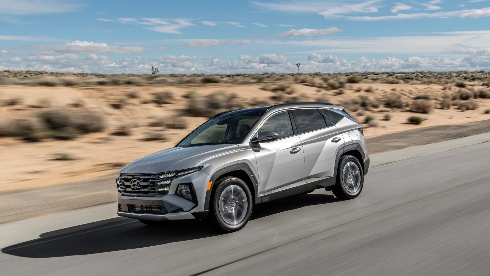 Hyundai Tucson PHEV 2025 màu xám bạc chạy trên đường nông thôn giữa sa mạc